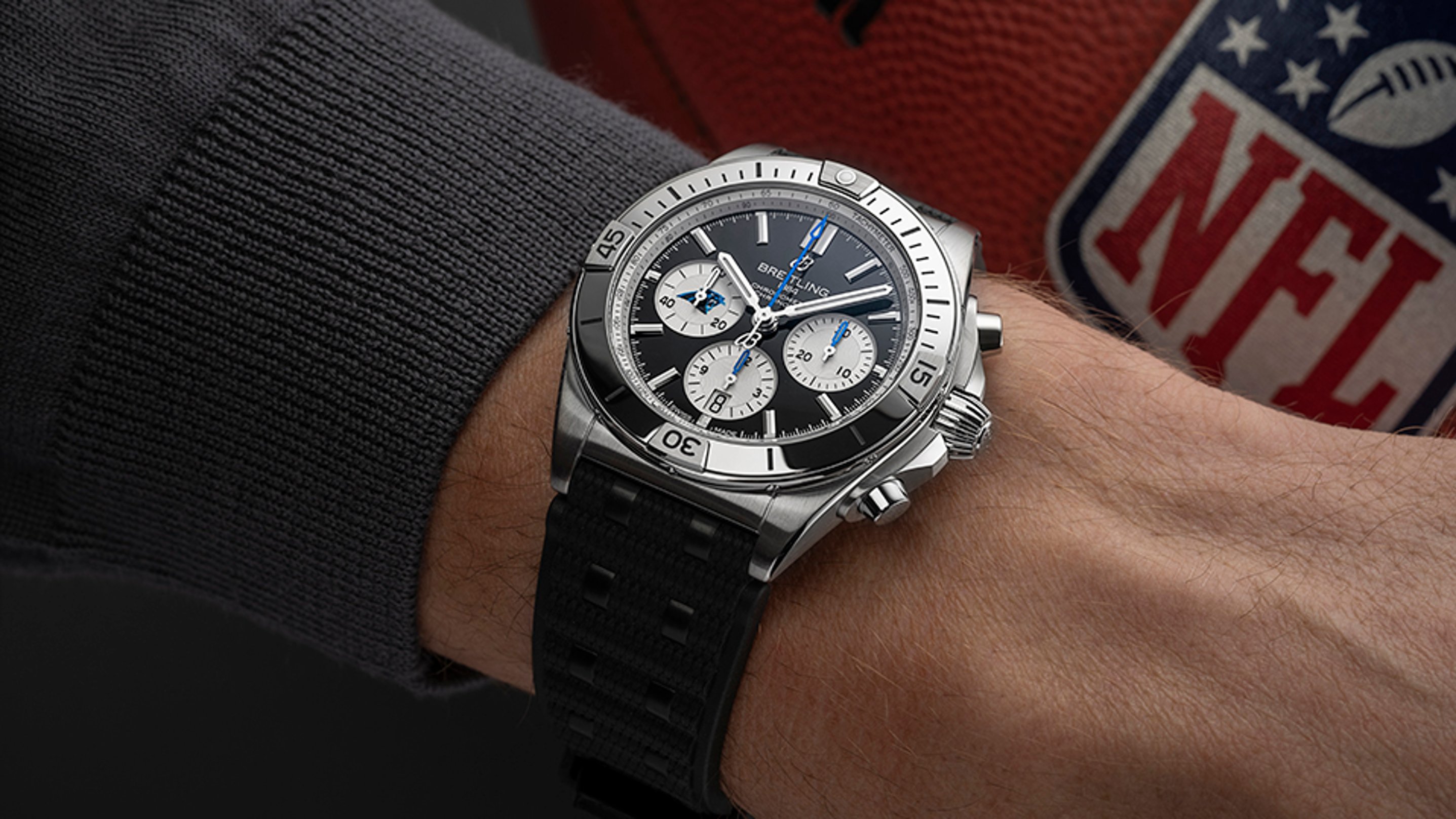 {generated} Breitling Chronomat with black dial and blue accents worn near an NFL football, highlighting Carolina Panthers spirit.