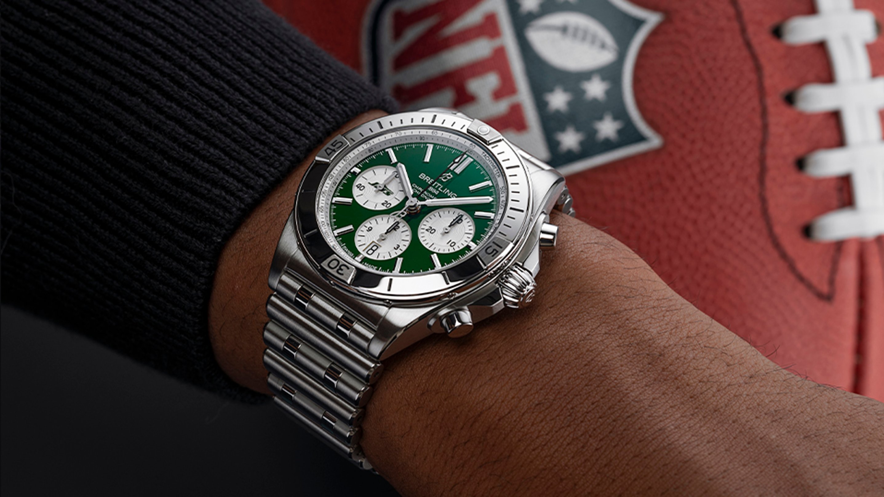 {generated} Breitling Chronomat with green dial on a wrist, set against a New York Jets NFL football for team-inspired styling