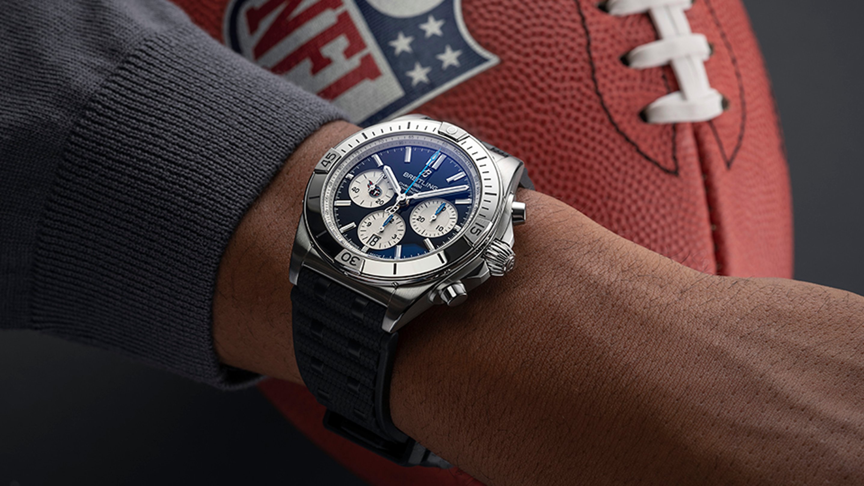 {generated} Breitling Chronomat à cadran bleu au poignet près d’un ballon NFL, soulignant son style pour les fans des Tennessee Titans