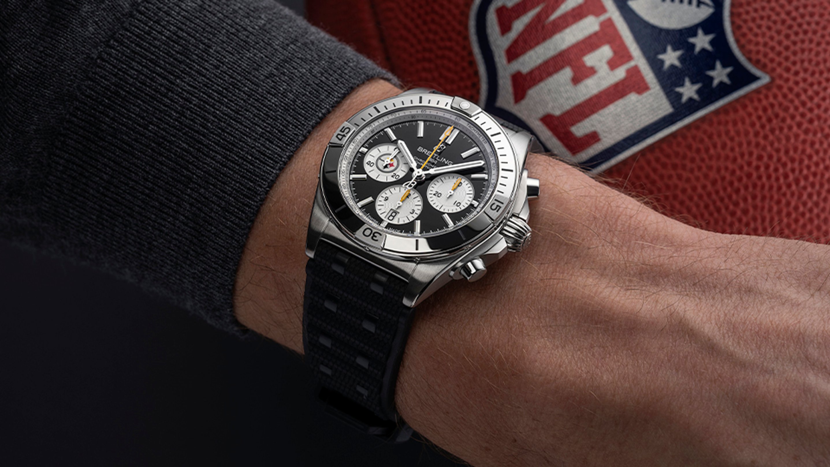 {generated} Breitling Chronomat on a wrist with an NFL football in view, pairing its bold chronograph style with Pittsburgh Steelers spirit
