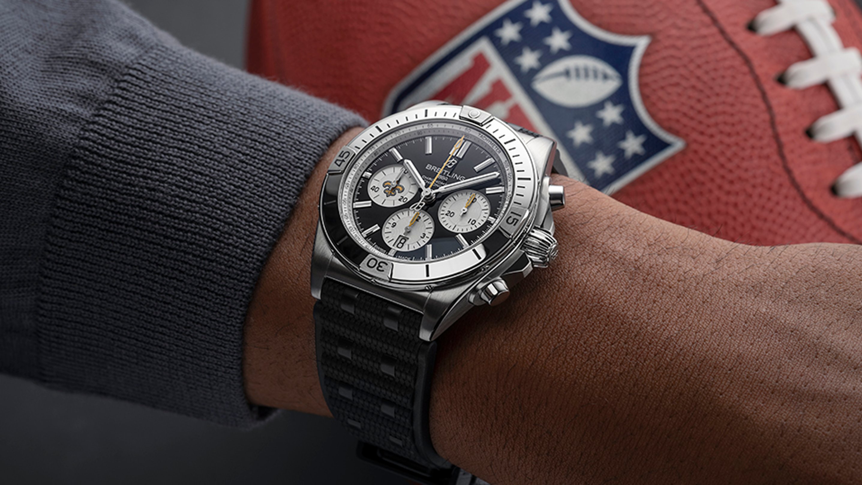 {generated} Breitling Chronomat New Orleans Saints watch on a wrist beside an NFL football, emphasizing team colors and refined design