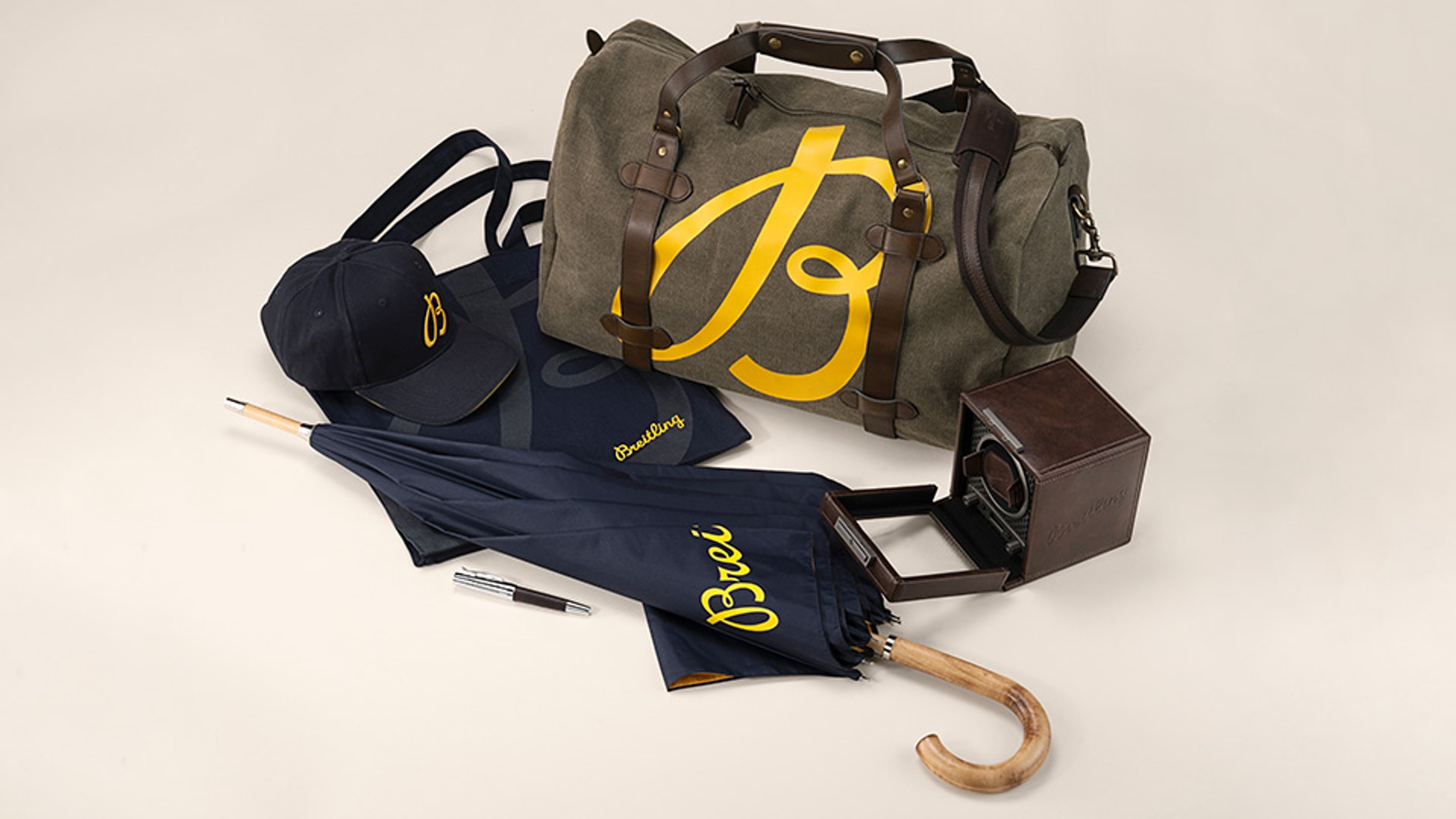 {generated} Ensemble Breitling avec sac de voyage en toile, casquette, parapluie, tote bag, stylo et remontoir en cuir soigneusement présenté.