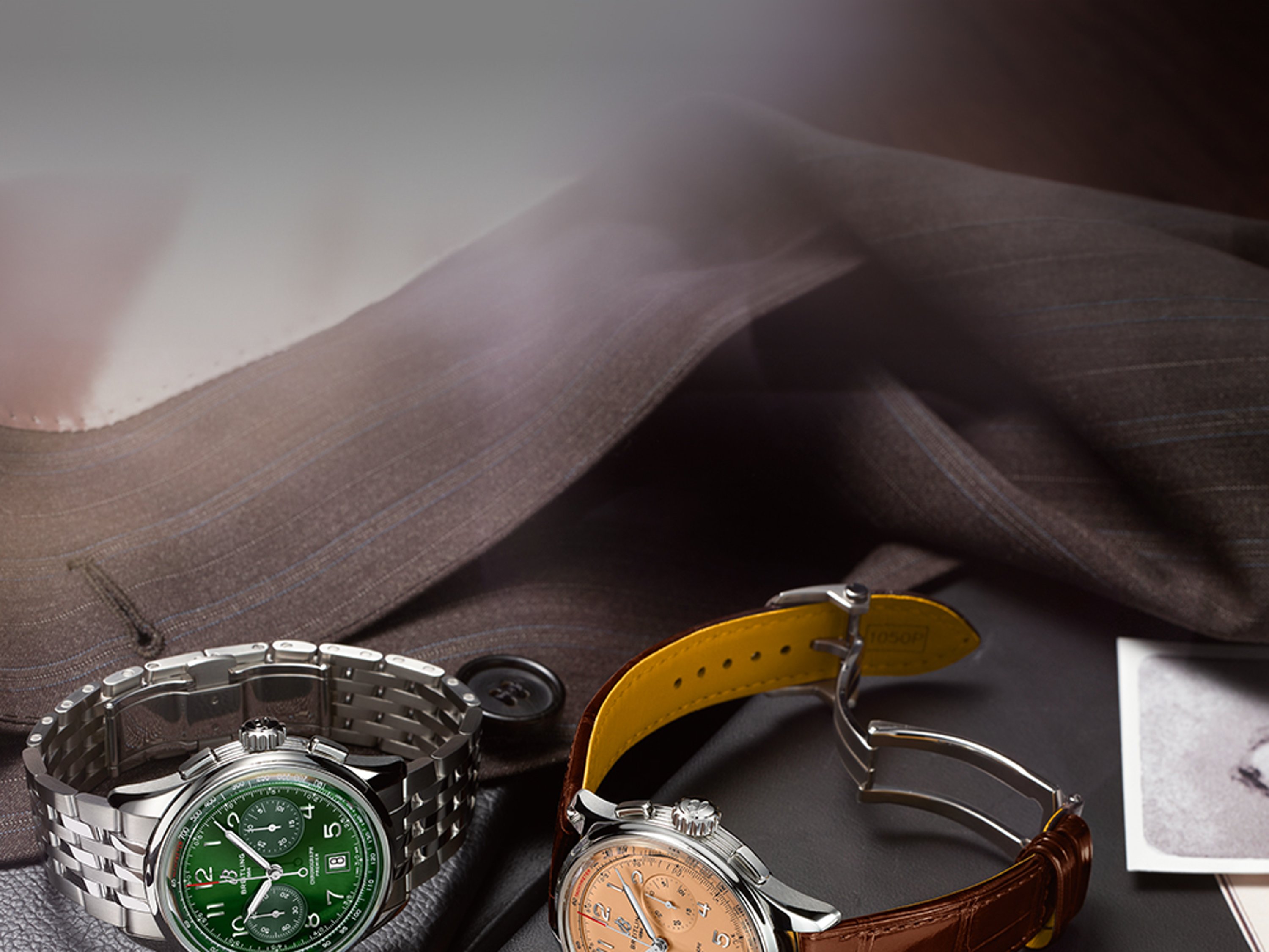 Three Premier watches with elegant bracelets lie on black notebooks on a brown table.
