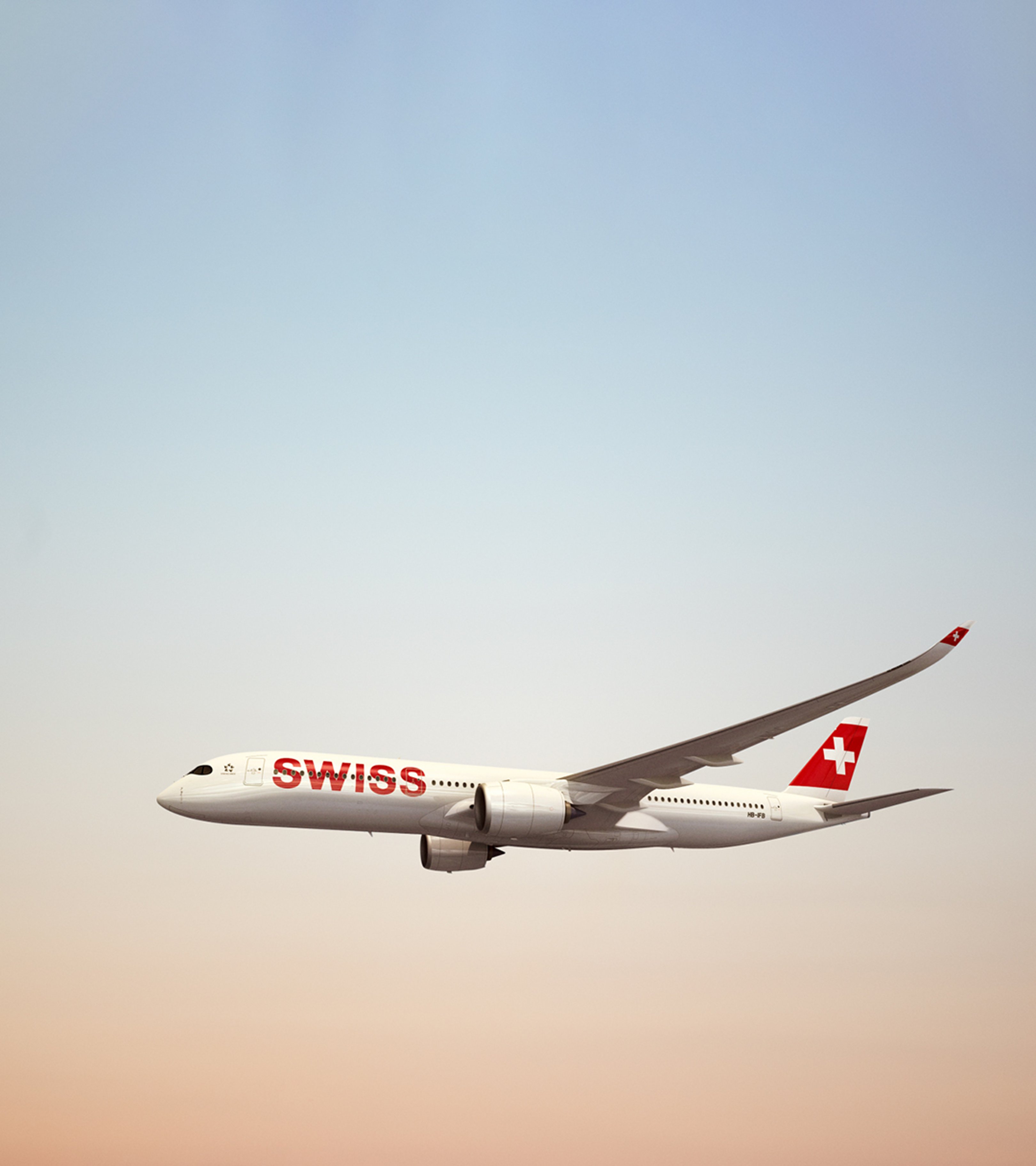 {generated} SWISS aircraft cruising against a soft sunrise sky, highlighting its red tail emblem in a clean, expansive scene.
