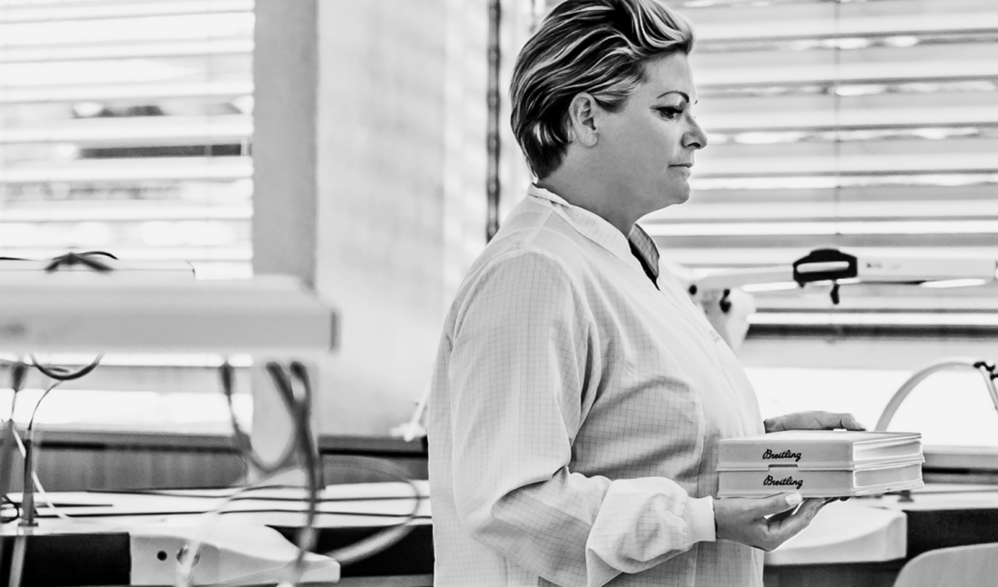 {generated} Watchmakers in a Breitling workshop collaborate at precision benches as trays are delivered, highlighting service expertise