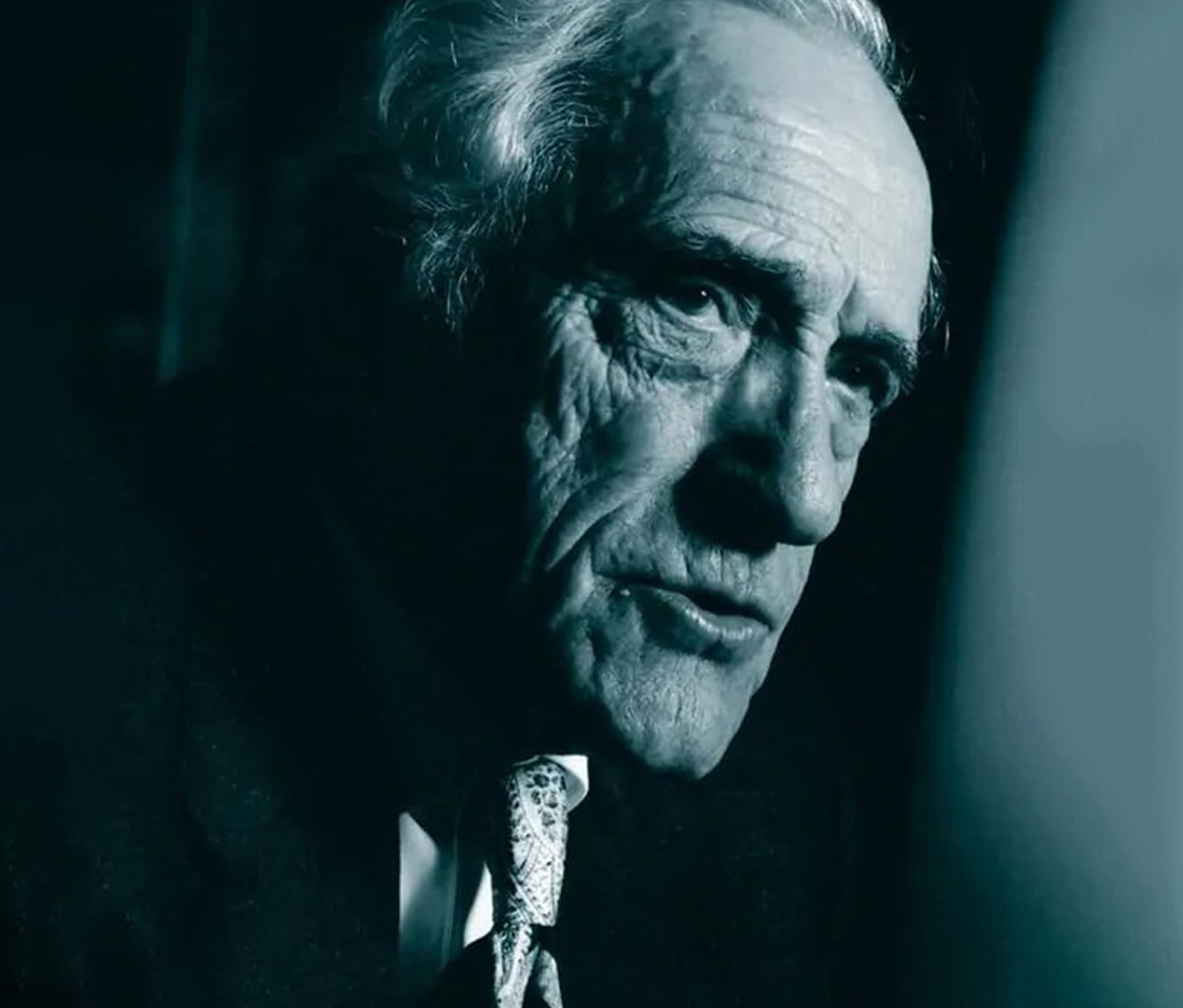 {generated} 身著深色西裝與圖案領帶的高齡人物在濃烈光影中呈現，散發出1979年代的氛圍感。