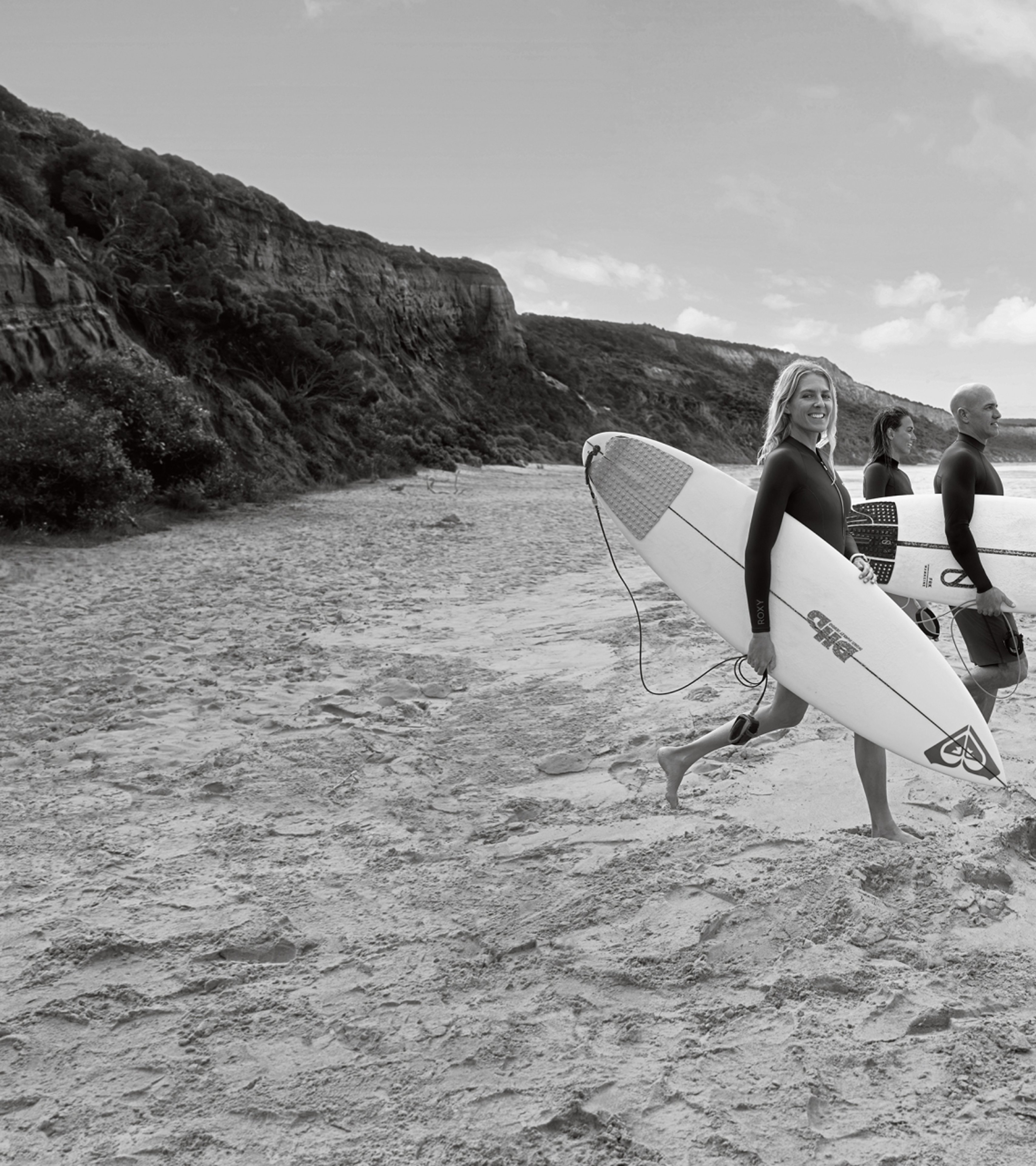 {generated} Three surfers holding boards stand on a quiet shoreline, evoking an adventurous coastal mood suited to newsletter signups.