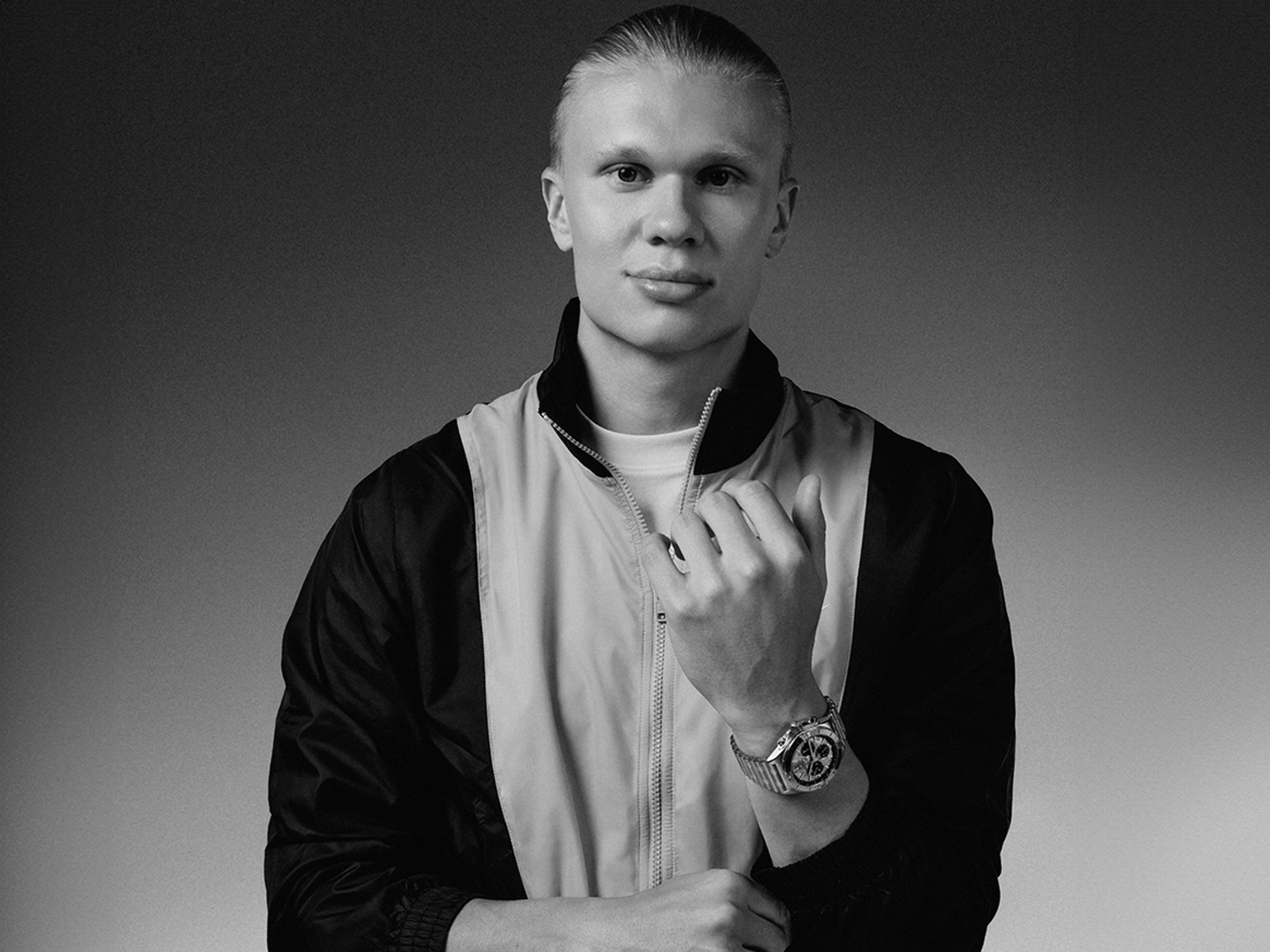 {generated} Erling Haaland figure in sporty jacket showcasing a Breitling watch on his wrist against a clean monochrome backdrop