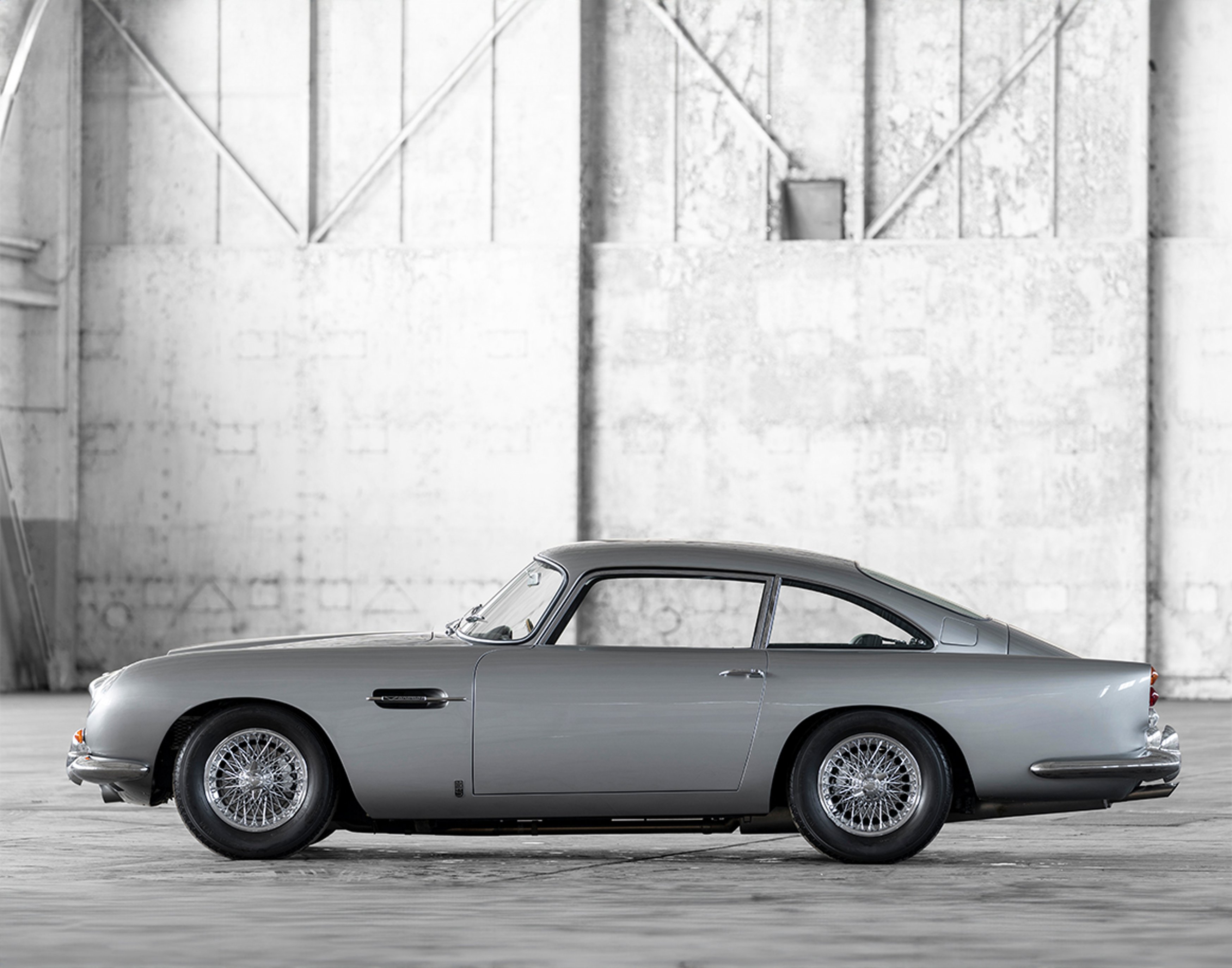 {generated} Sleek dark grey Aston Martin coupe highlighted in studio lighting, showcasing its sculpted lines and red-accented details.