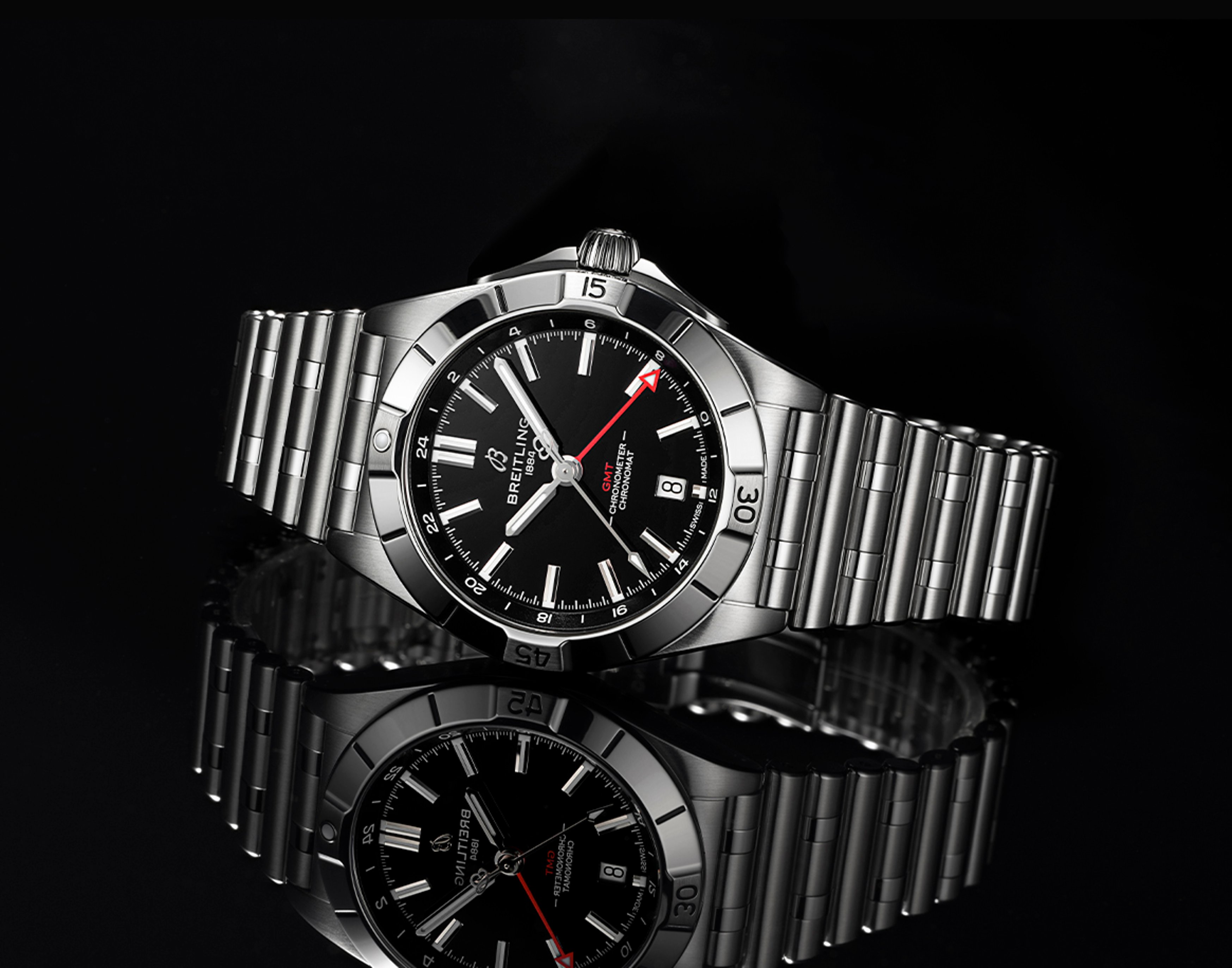 {generated} Breitling Chronomat GMT in polished steel with black dial and red GMT hand displayed against a reflective dark surface