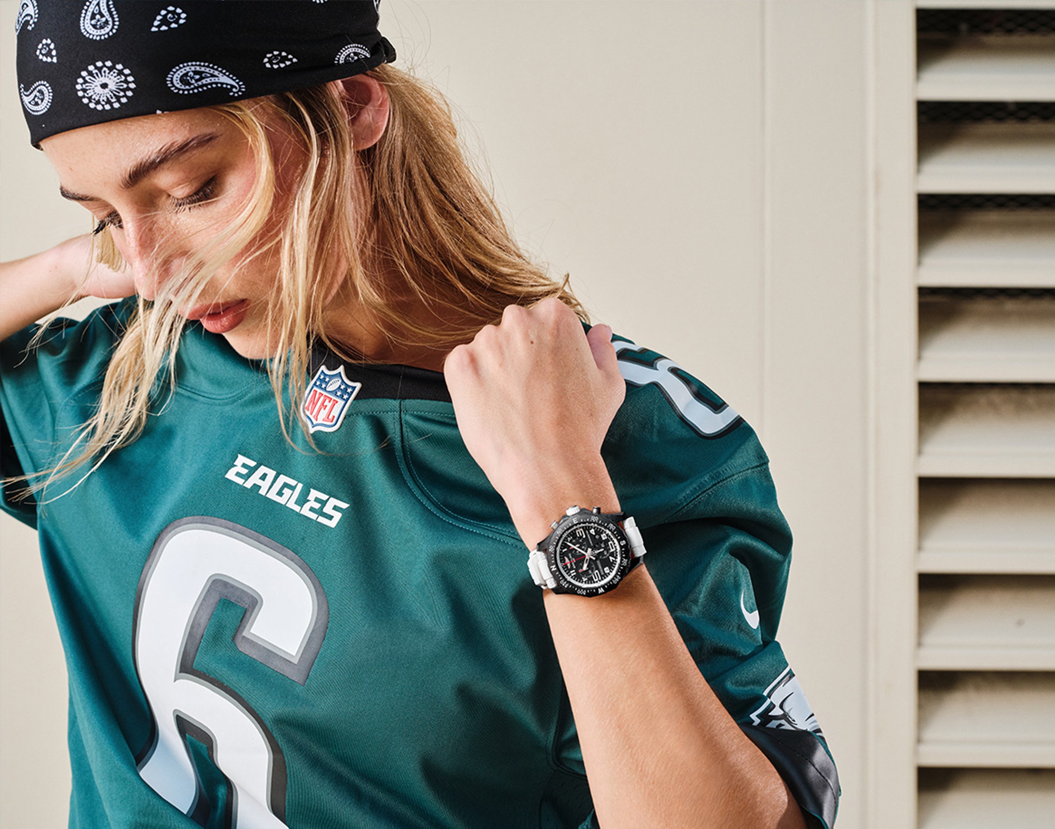 {generated} A person in an Eagles jersey shows a Breitling X NFL watch with a bold black dial and white strap, highlighting team pride.
