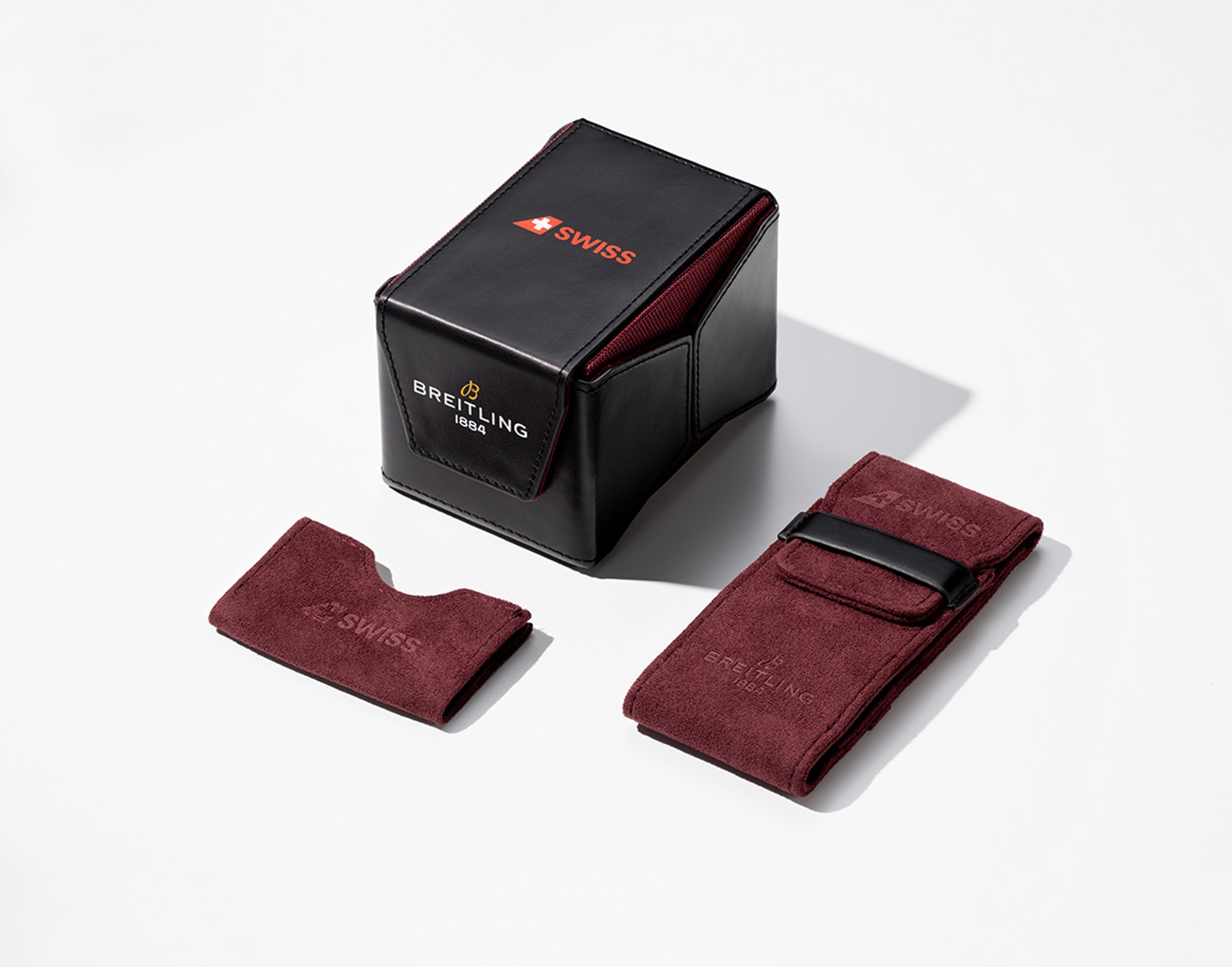 {generated} Breitling x Swiss collaborative set with a black box and burgundy travel pouches neatly arranged on a clean light surface