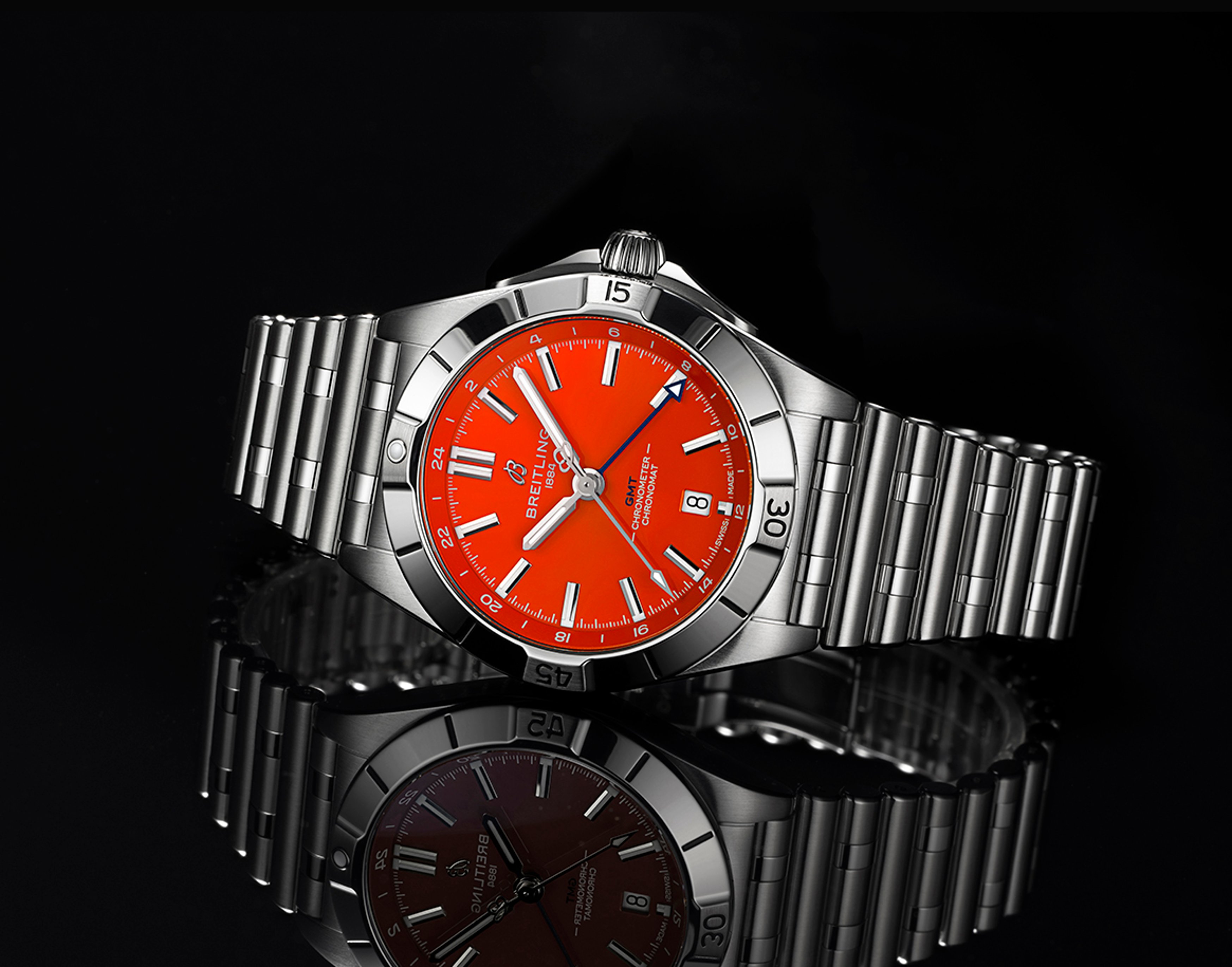 {generated} Breitling Chronomat Automatic GMT 40 with vivid orange dial and steel bracelet set on a sleek black reflective surface
