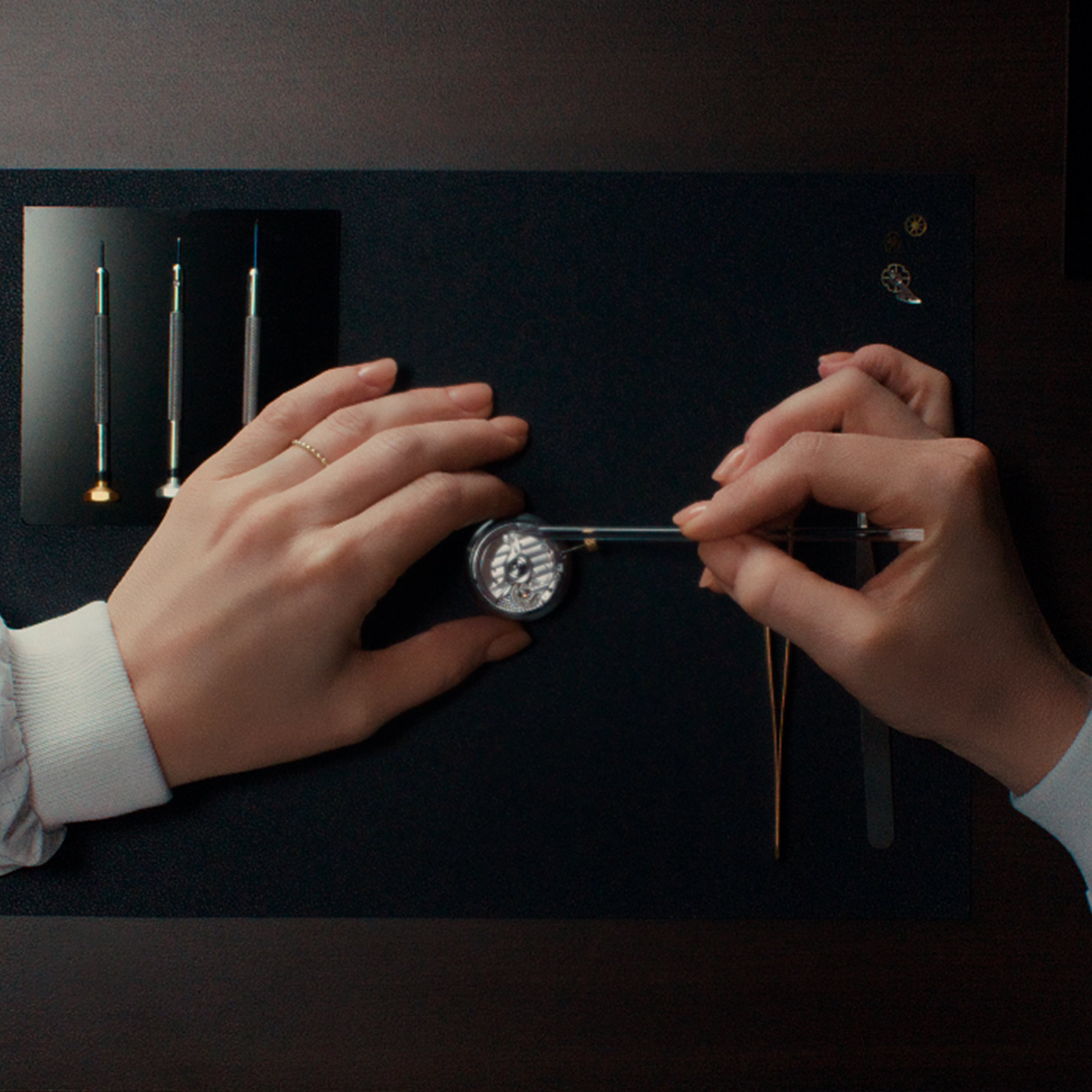 {generated} Hands assembling the Breitling Caliber B31 movement with precision tools on a dark workspace, highlighting fine craftsmanship