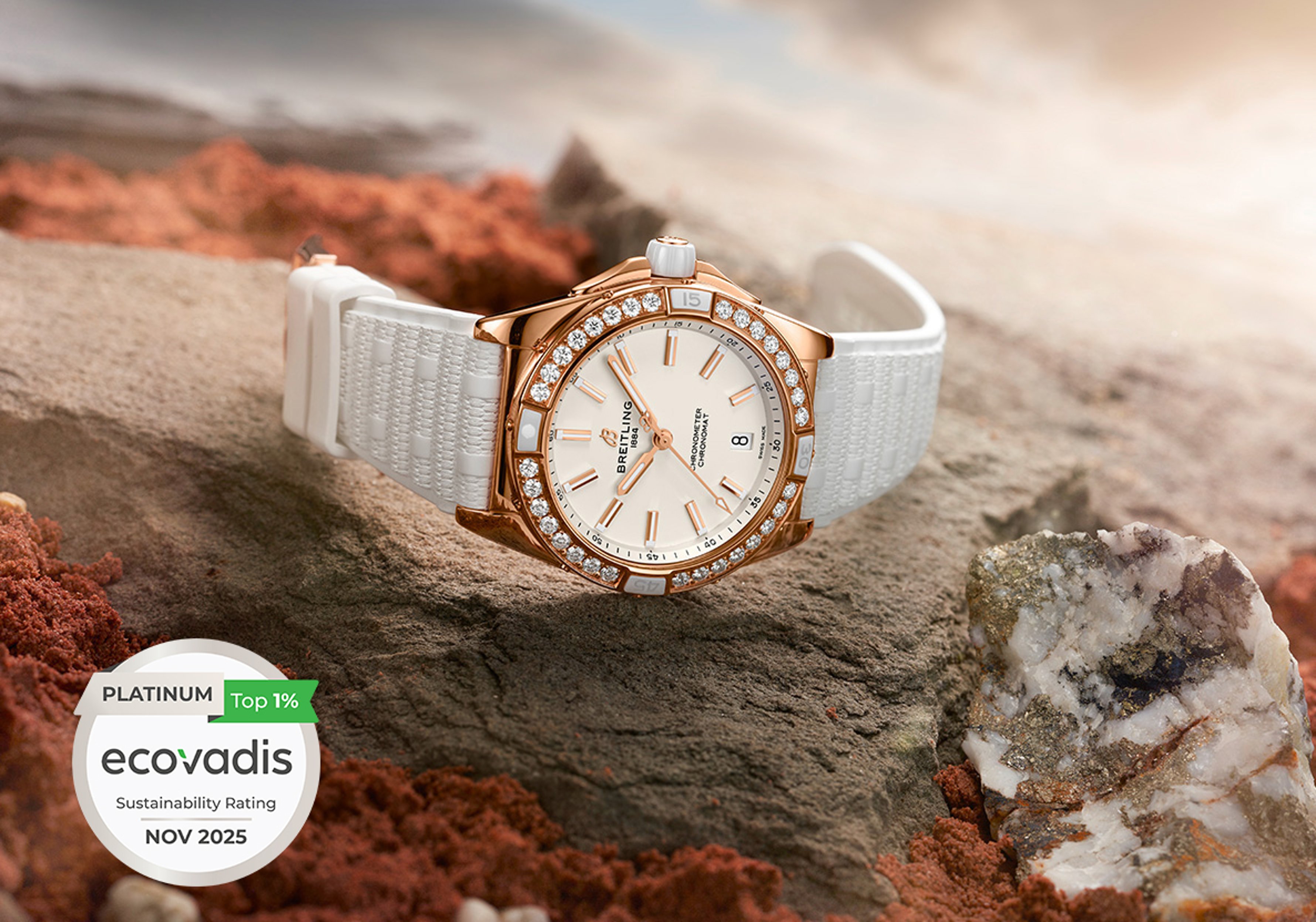 {generated} Breitling Chronomat à lunette diamantée et bracelet blanc posé sur un sol rocheux près d’un badge EcoVadis