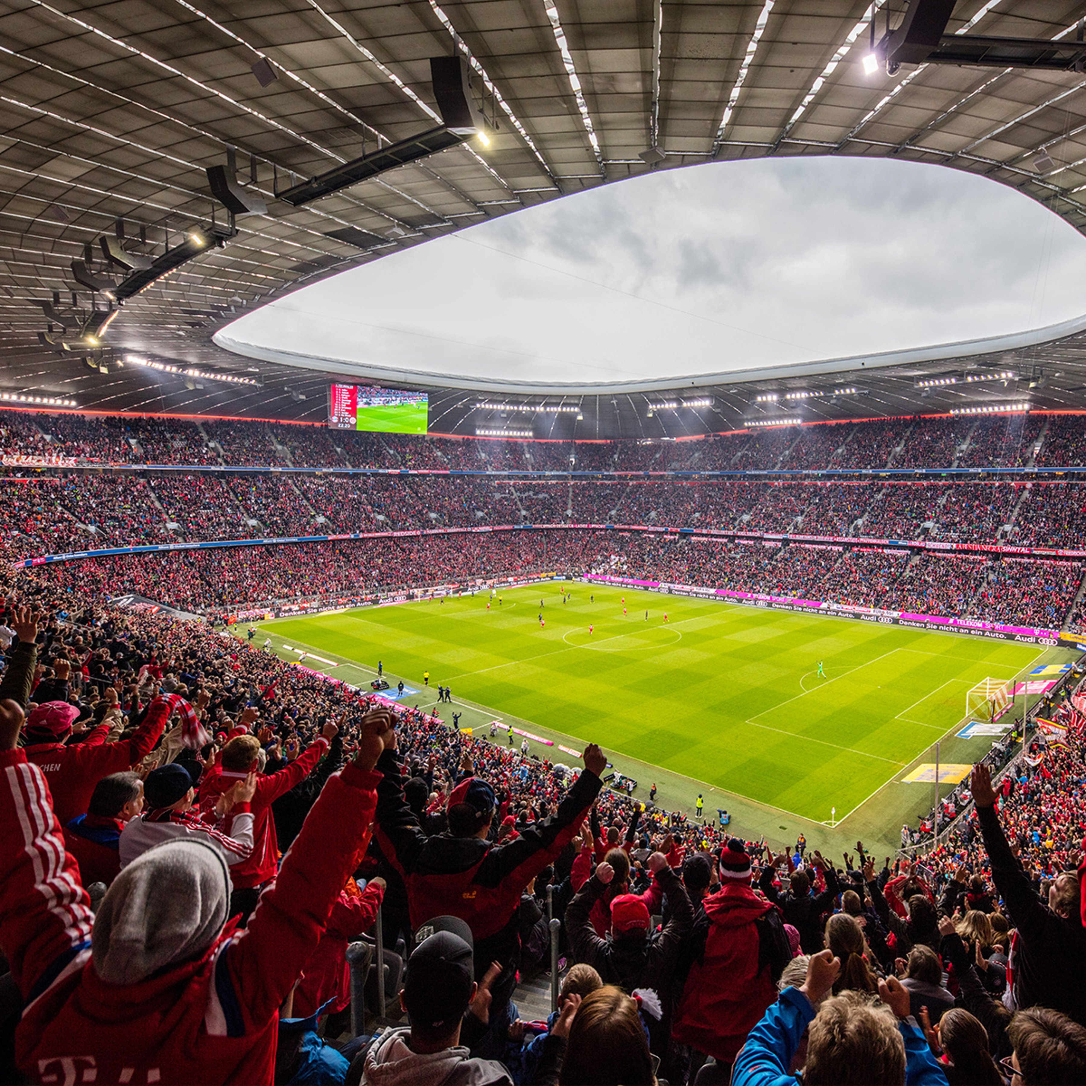 {generated} 滿座的拜仁球場中觀眾歡呼,球員在明亮球場上於現代弧形屋頂下展開比賽。
