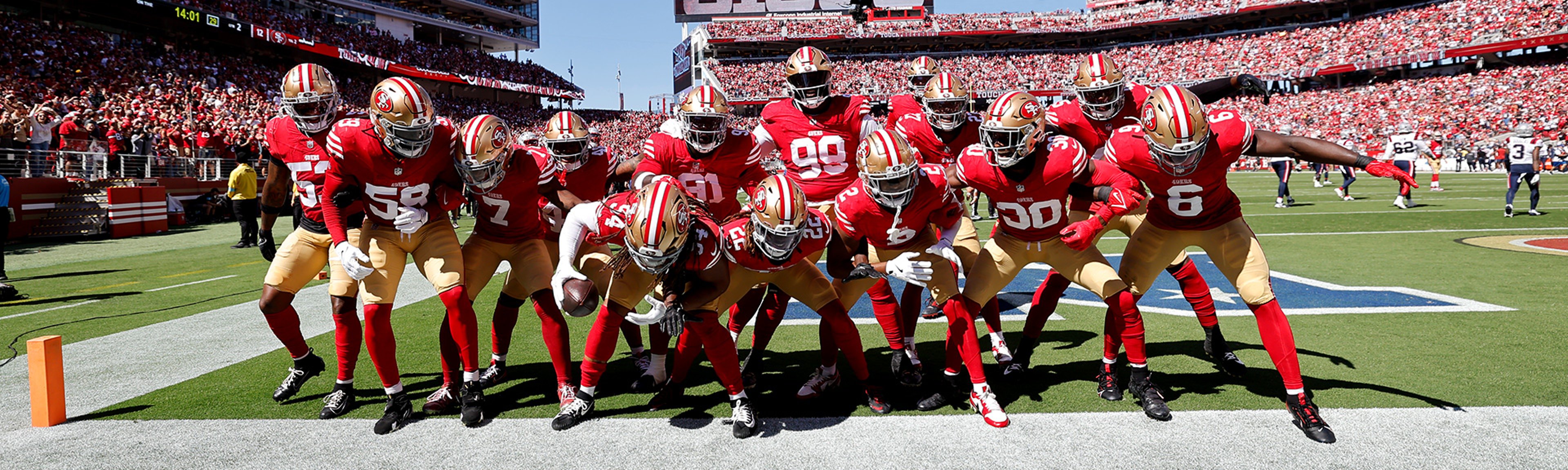 {generated} Jugadores de los San Francisco 49ers unidos en rojo y dorado en el campo, mostrando espíritu de equipo con el vínculo NFL de Breitling
