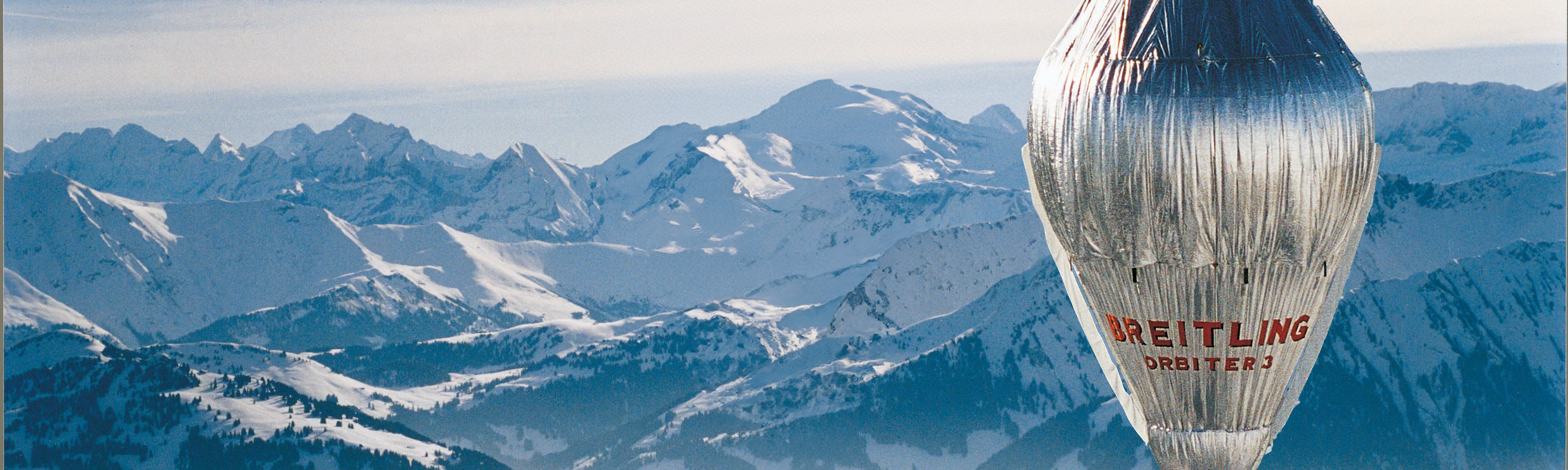 {generated} Breitling Orbiter 3 hot-air balloon gliding above expansive snowy mountain peaks, highlighting adventurous spirit.