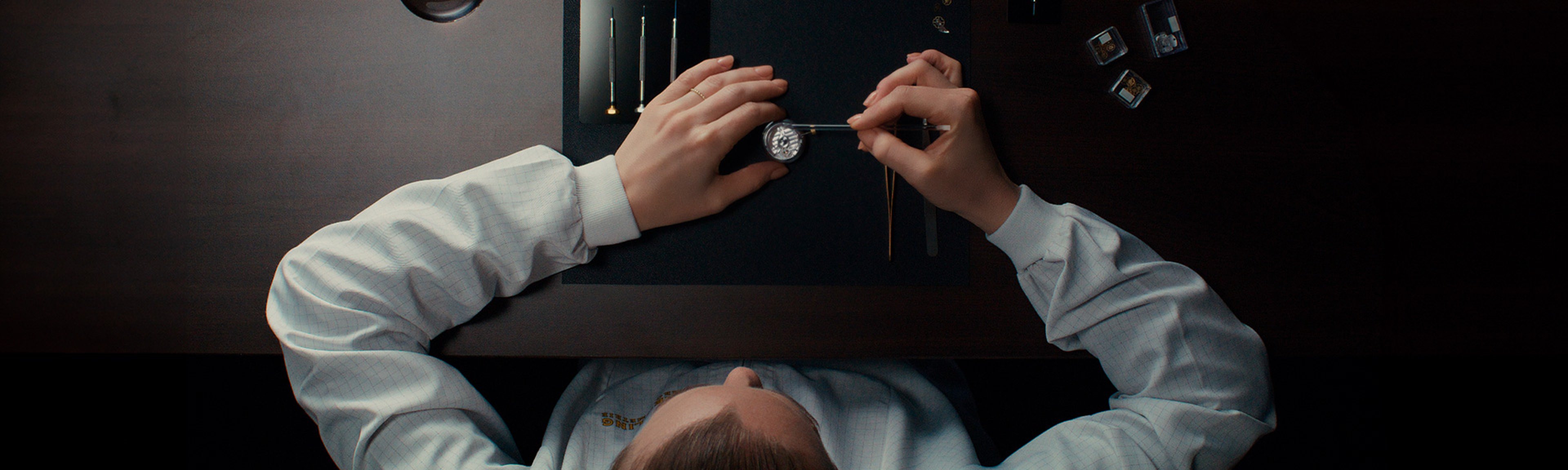 {generated} A Breitling technician carefully assembles a watch movement with precision tools, highlighting expert service craftsmanship.