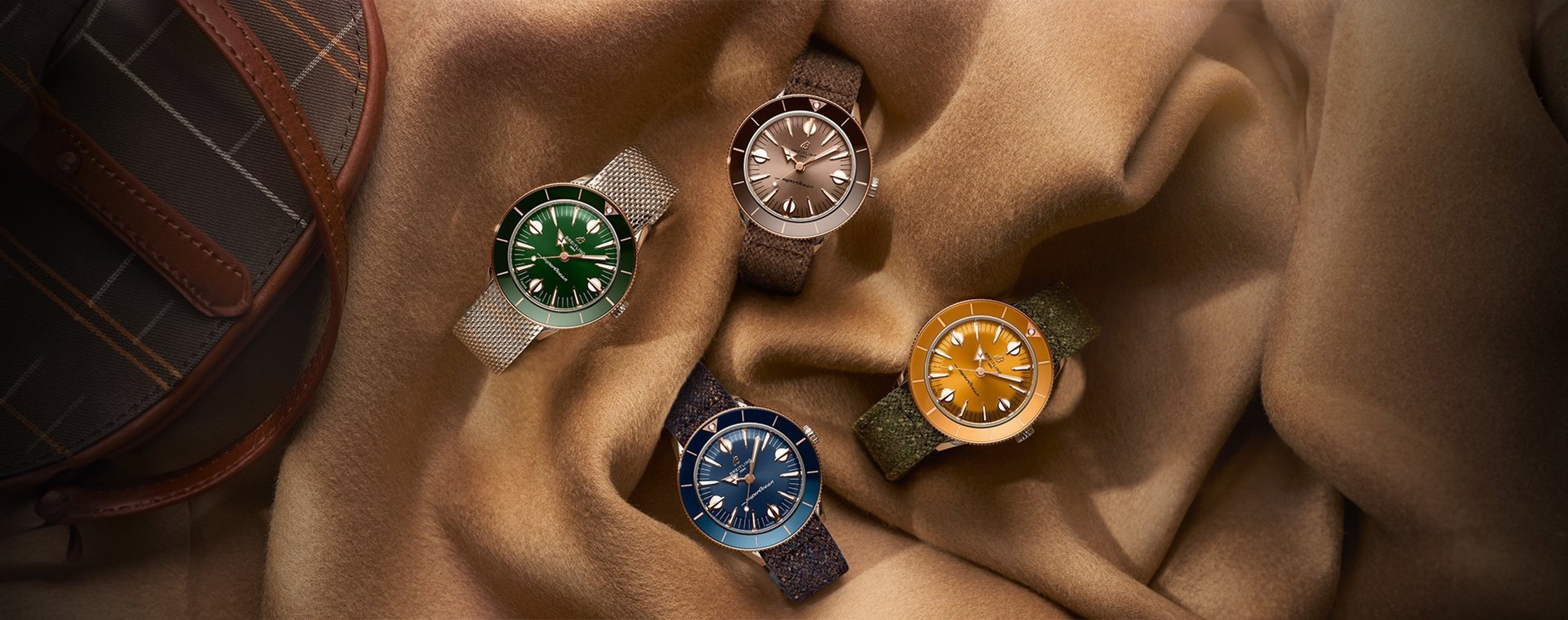 {generated} Orologi Breitling Superocean ’57 verde, taupe, blu e ambra disposti su un tessuto morbido per valorizzarne il design
