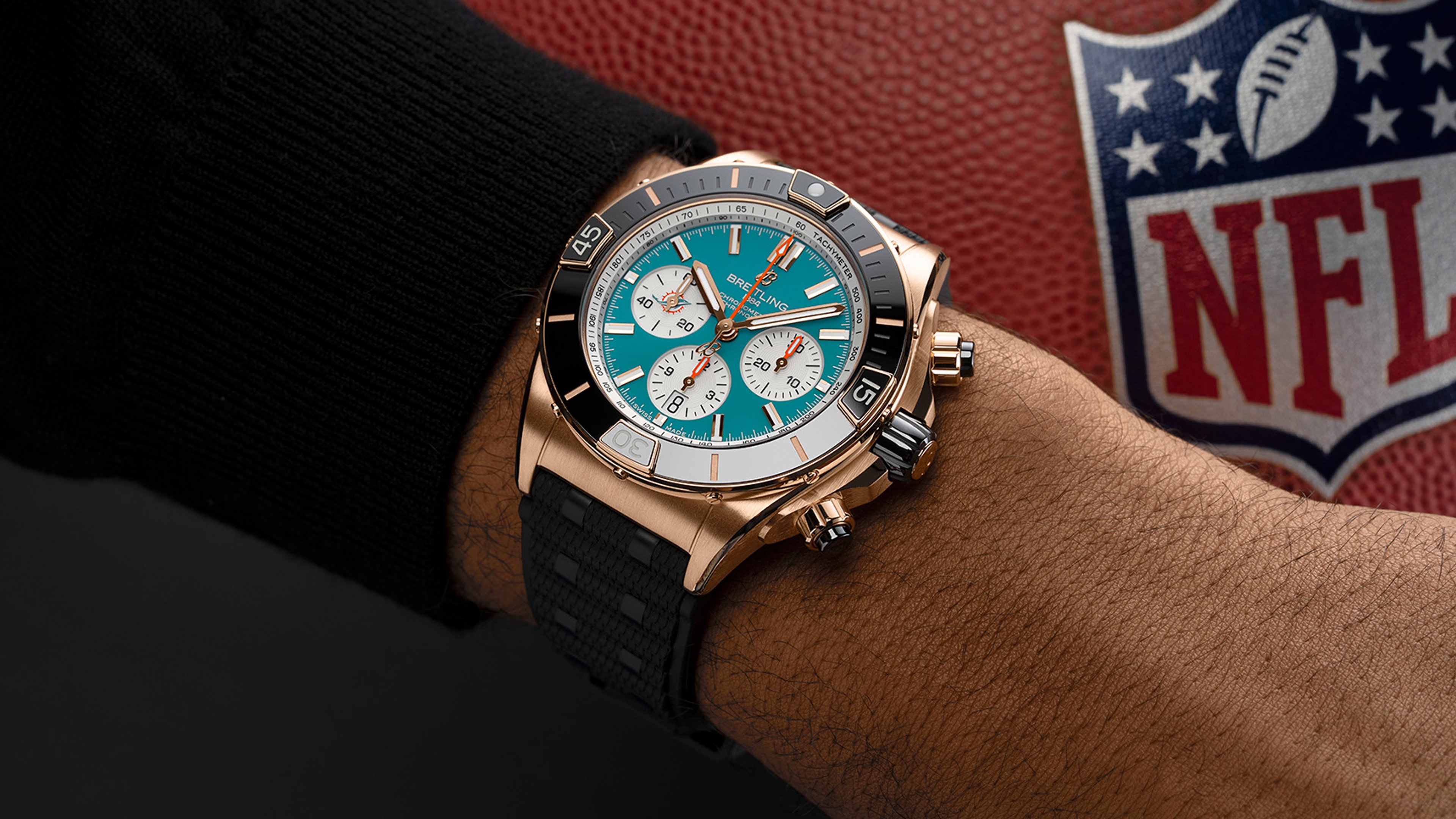{generated} Breitling Chronomat B01 42 in Miami Dolphins colors worn near an NFL football, highlighting bold sport styling.