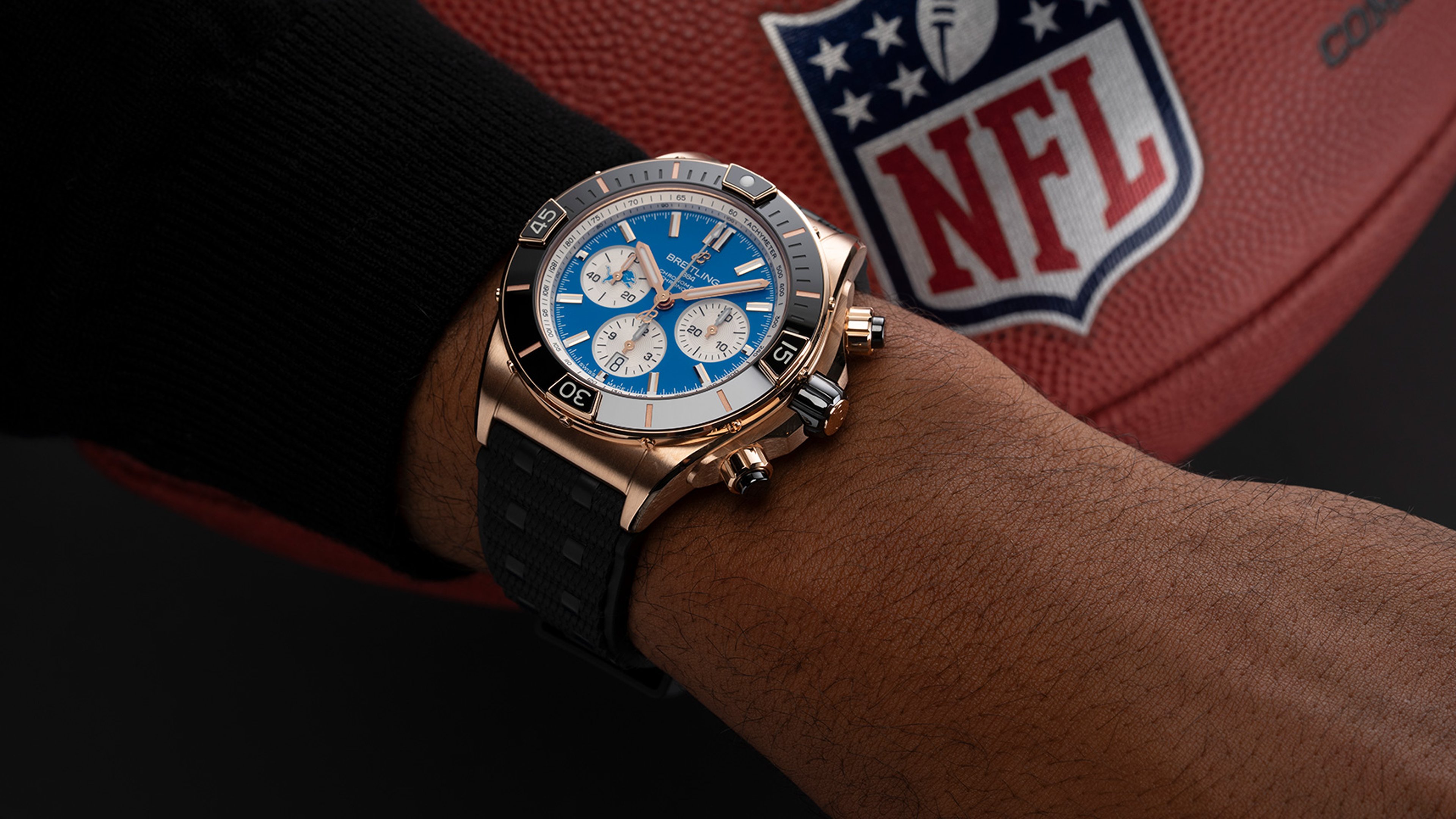 {generated} Breitling chronograph with blue dial on wrist shown against an NFL football, highlighting Detroit Lions themed styling.