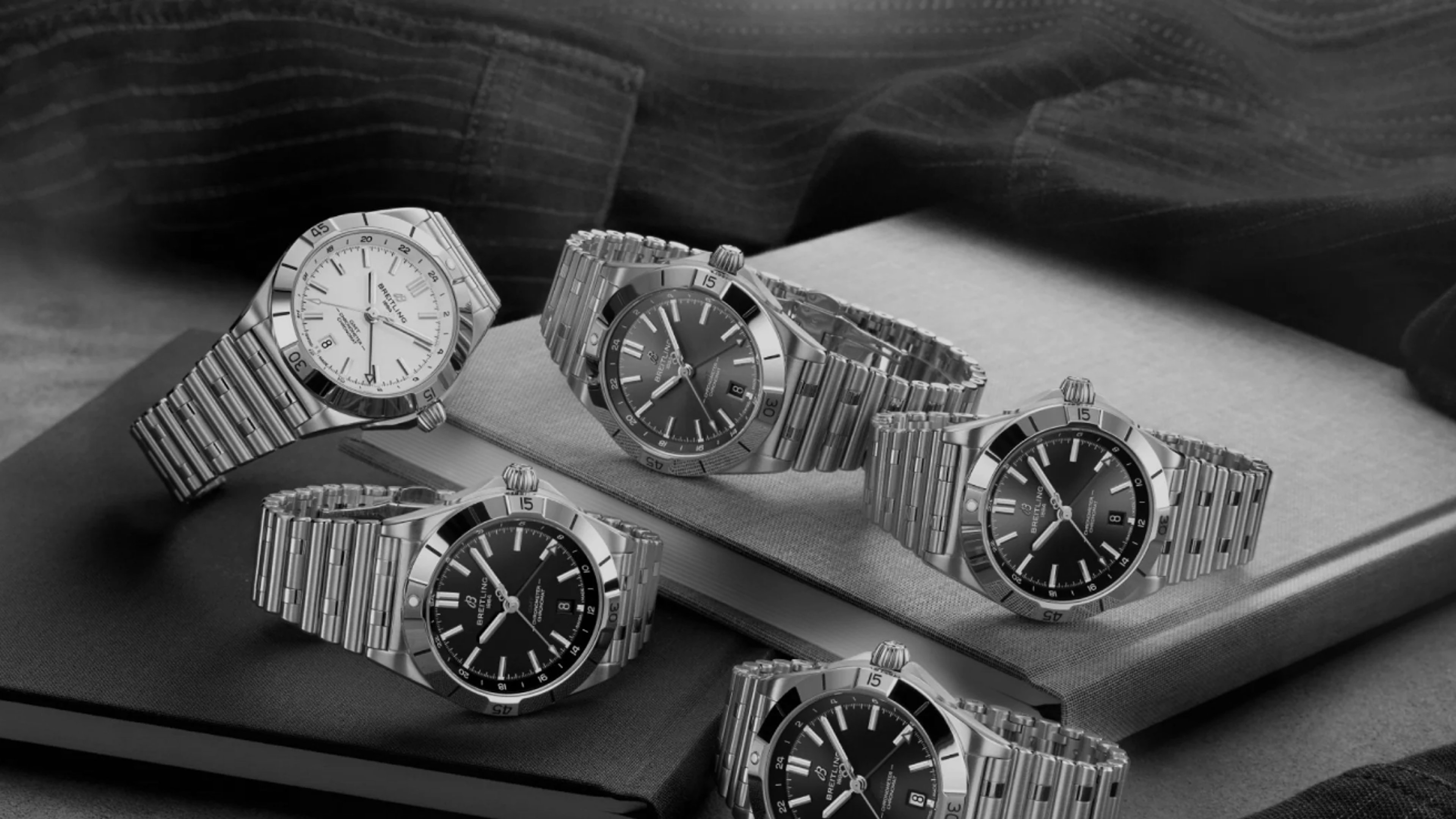 {generated} Breitling Chronomat watches arranged on books, showcasing polished steel cases and varied dials in a refined setting.