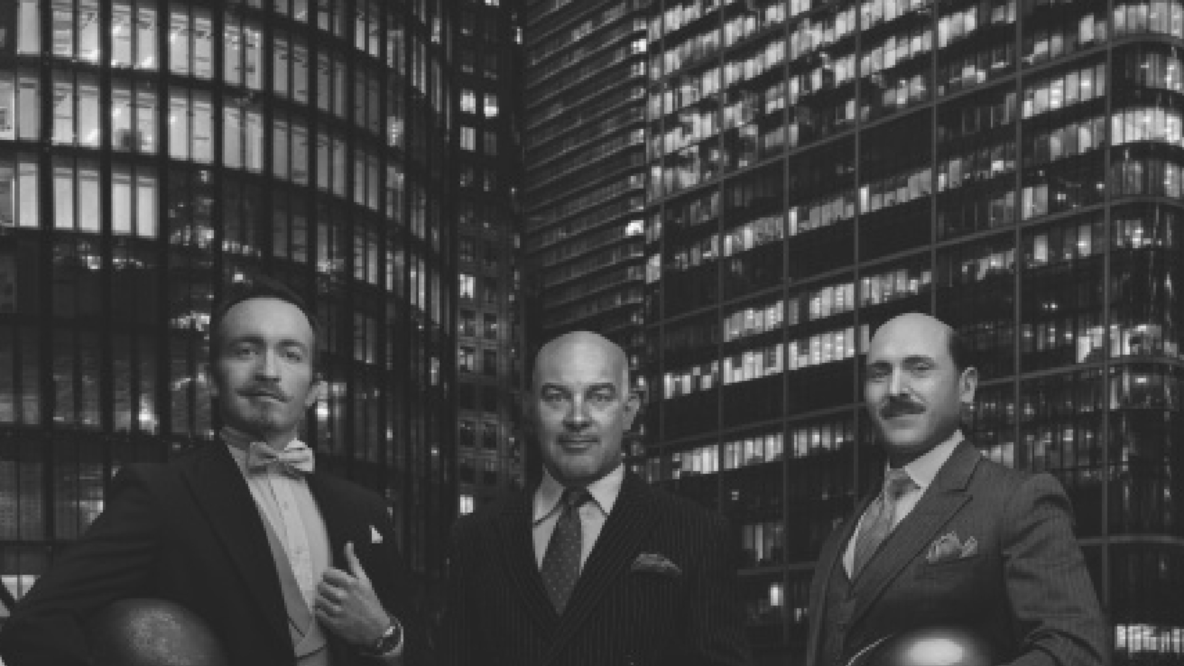 {generated} Three suited men holding helmets before a night city skyline, each wearing a Breitling watch to convey refined style