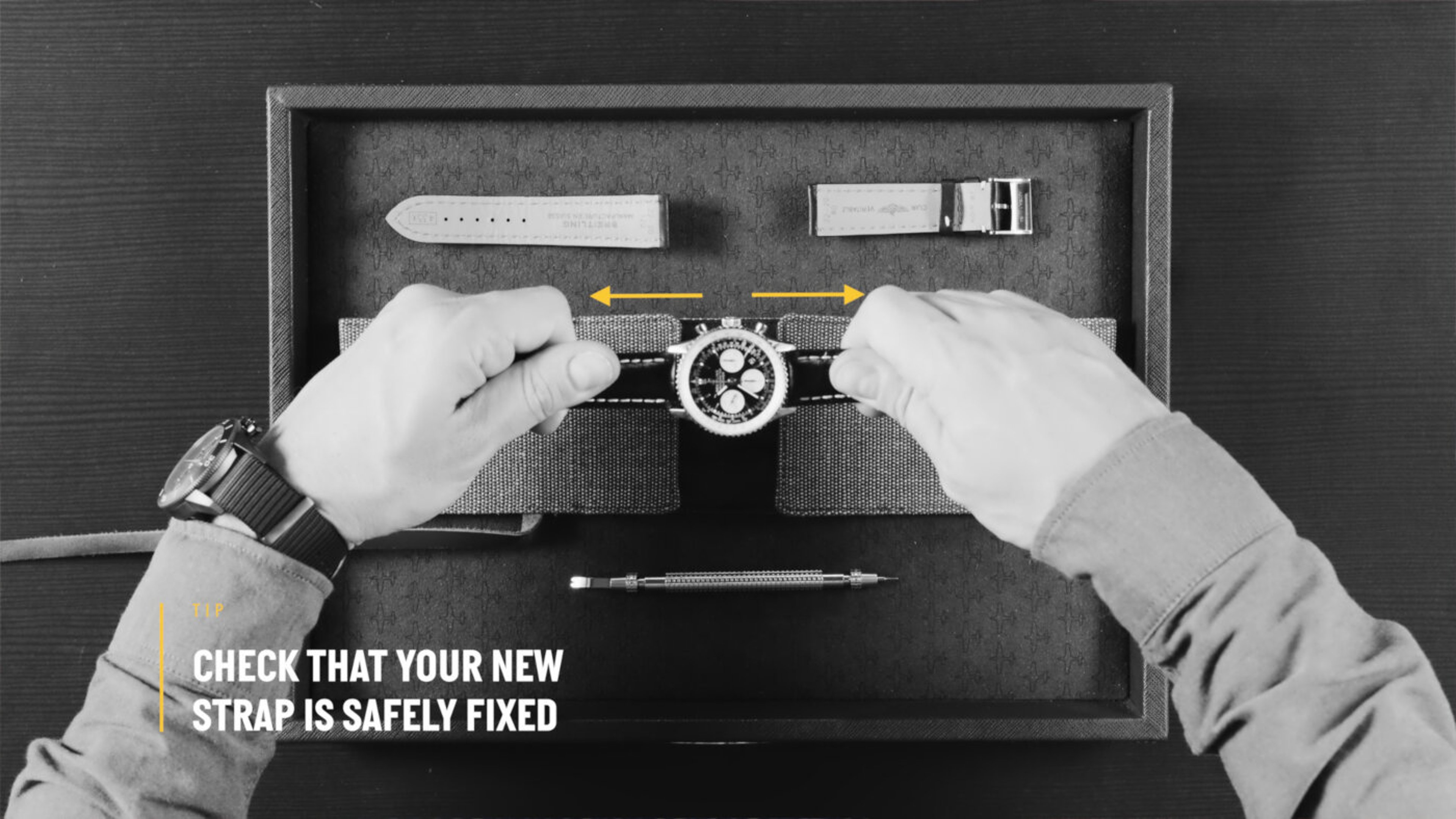 {generated} Hands testing a secured Breitling watch strap over a cushioned case, with tools and extra bands arranged neatly above.