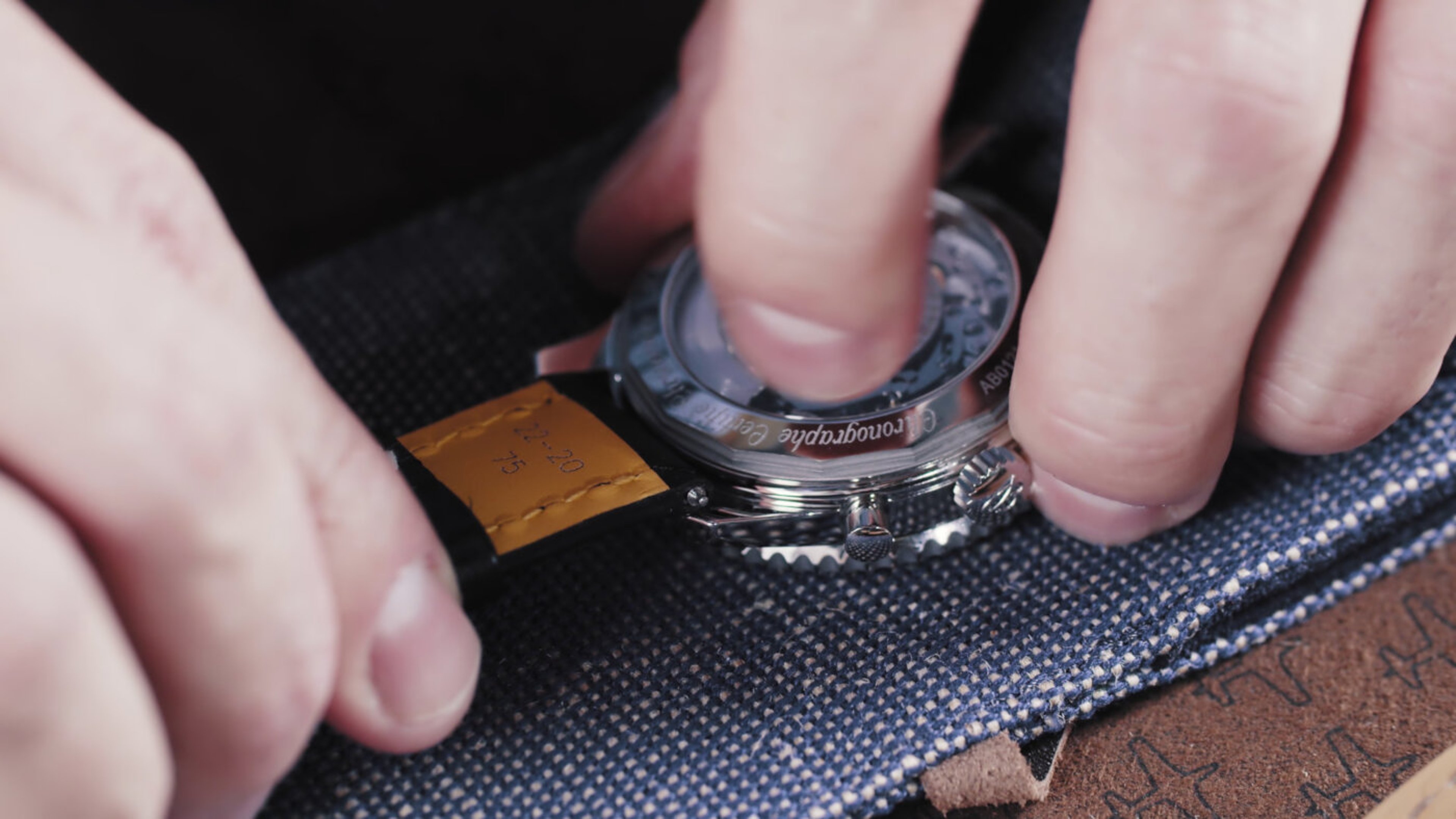{generated} Hands secure a Breitling watch by fastening the strap to the polished case, highlighting step 3 of careful assembly