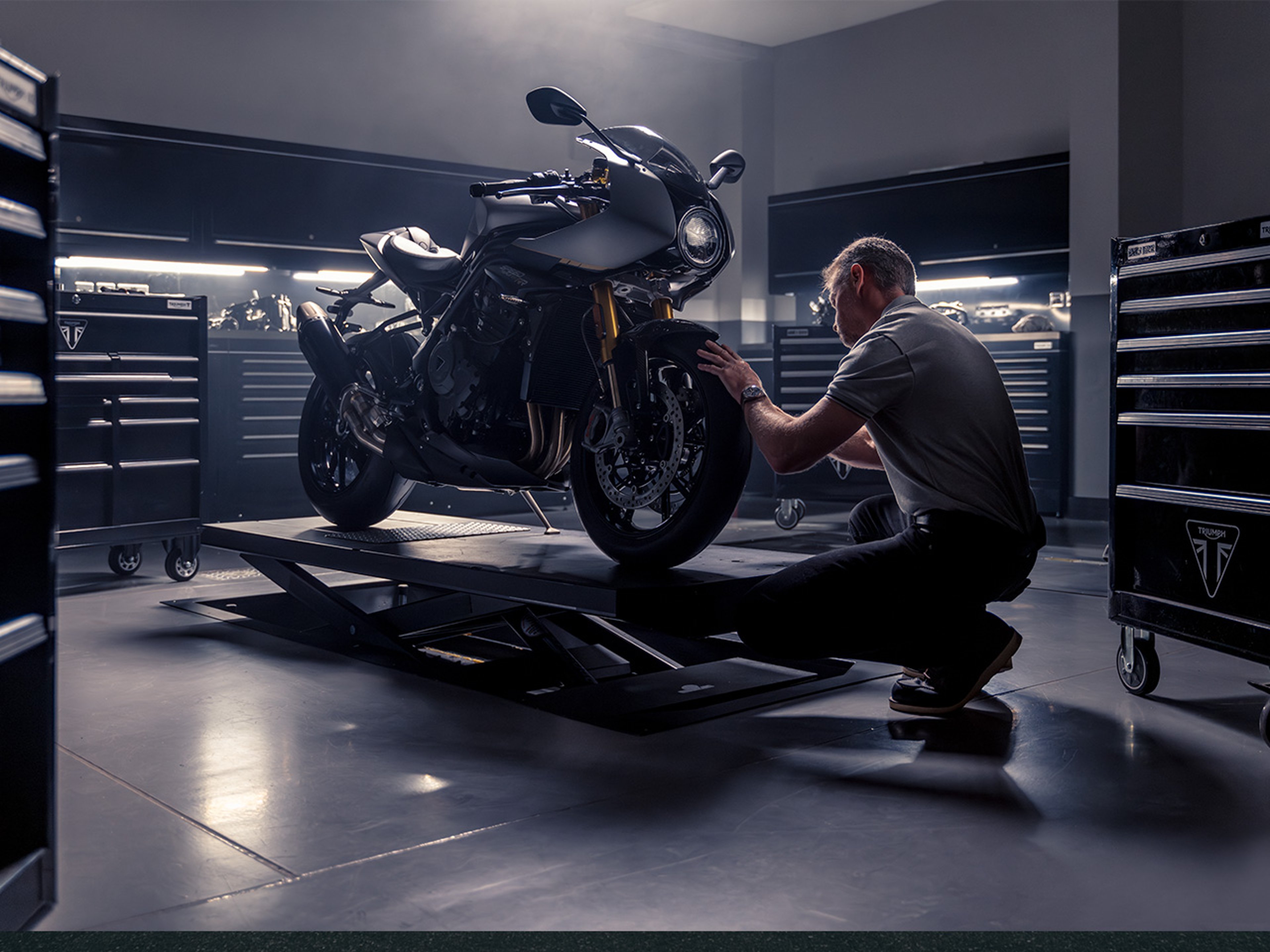 {generated} Mechanic assessing a motorcycle in a refined workshop, evoking the rugged Breitling land lifestyle and performance spirit