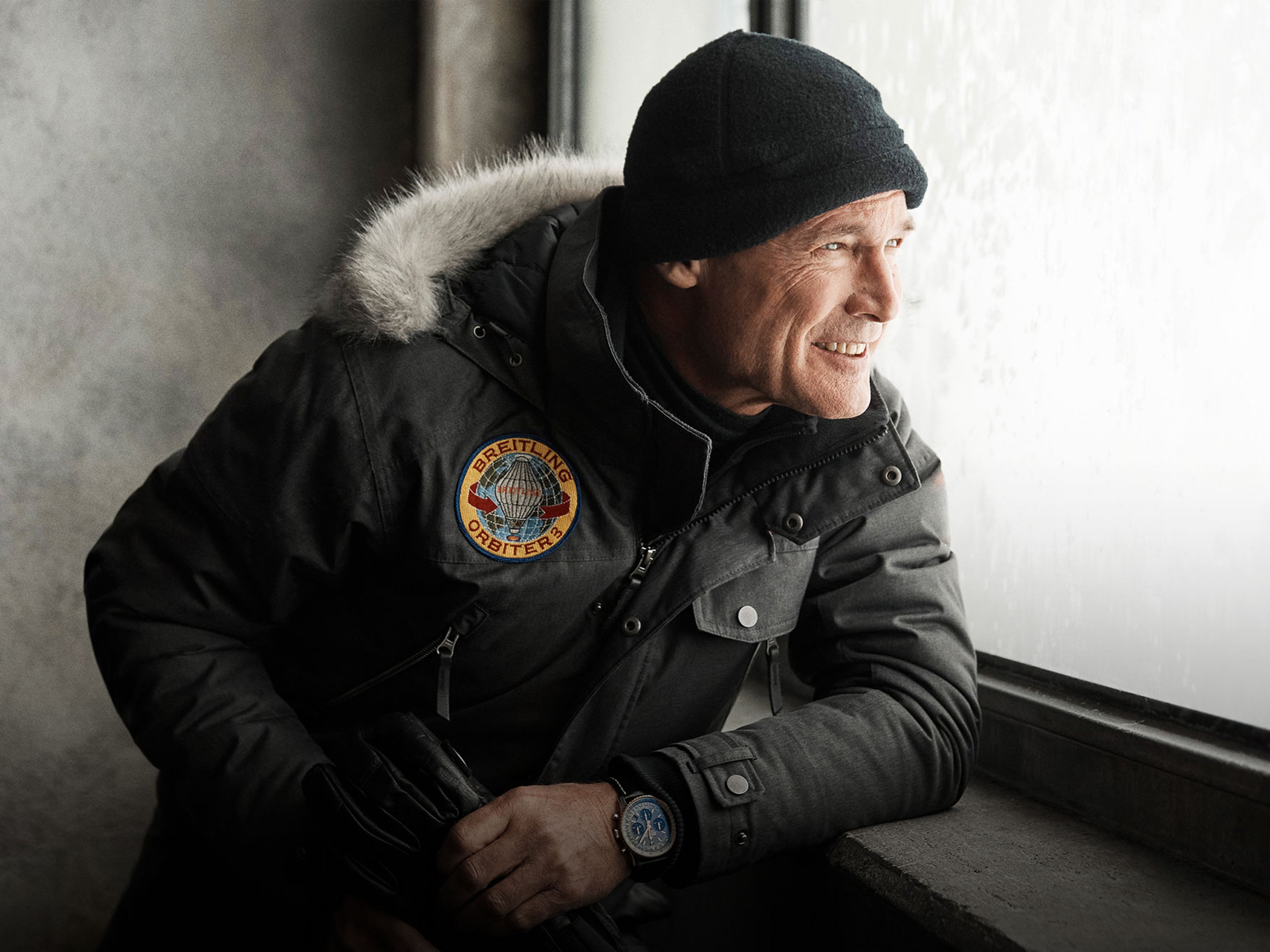 {generated} A bundled-up figure by a frosted window wearing a Breitling jacket and Breitling watch while holding gloves
