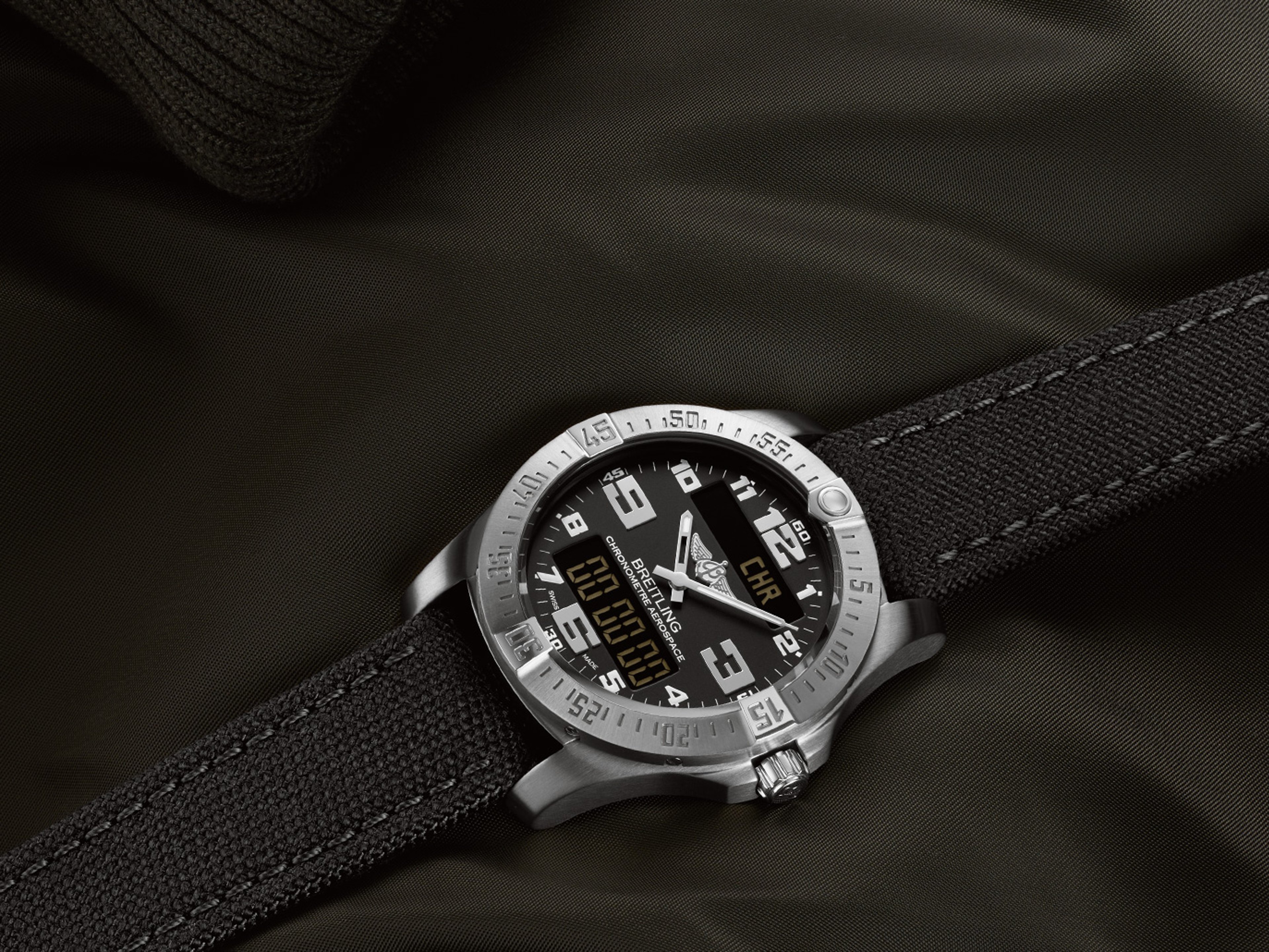 {generated} Breitling watch with black dial and fabric strap resting on dark textured fabric, highlighting rugged detailing and finish