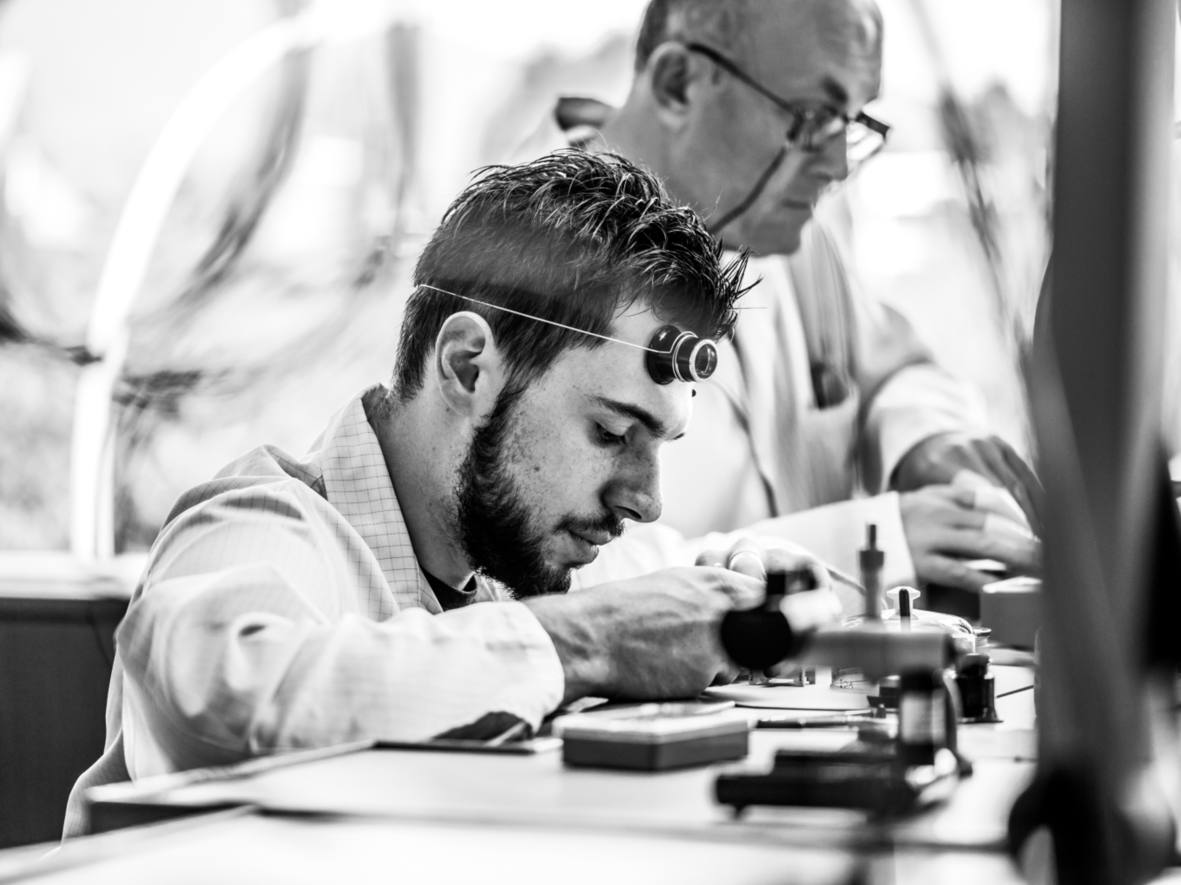 {generated} Watchmakers performing precise Breitling Emergency service work at a bench with tools and components under focused lighting.