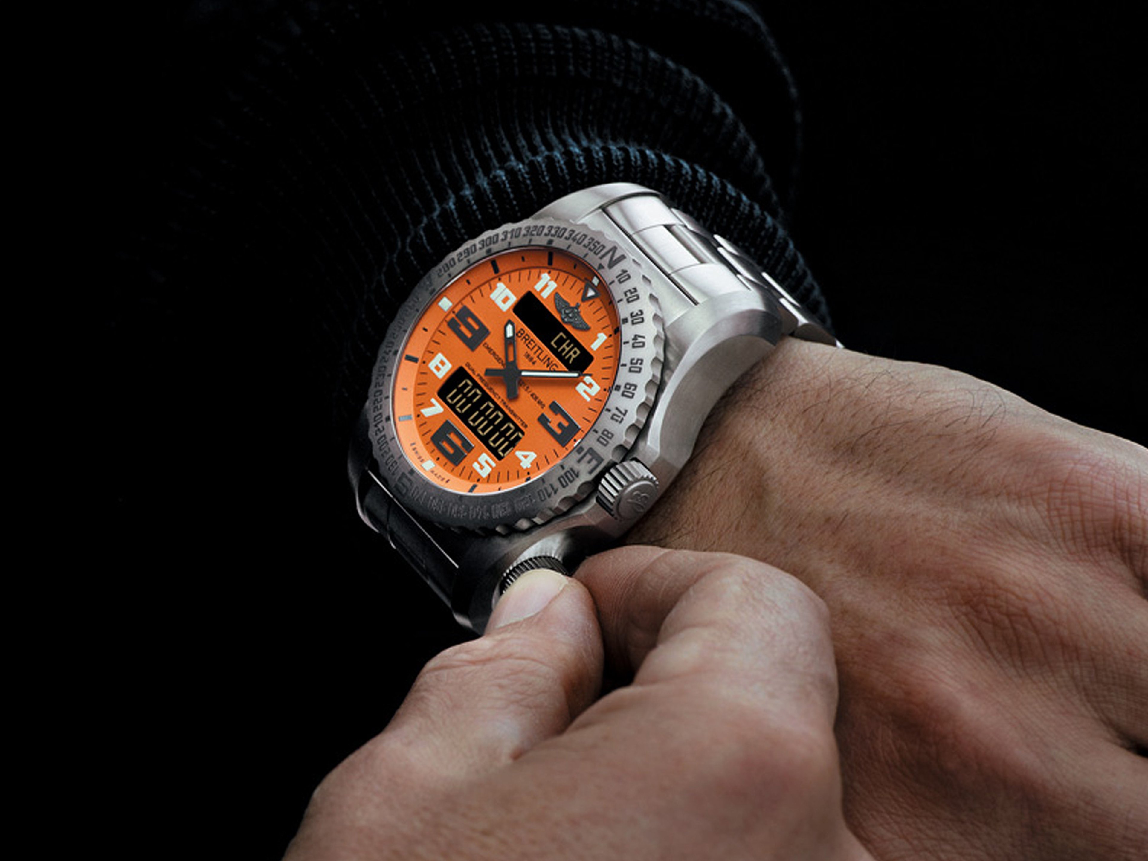 {generated} Breitling Emergency au cadran orange vif et affichage digital tandis qu’une main règle la couronne pour une précision optimale
