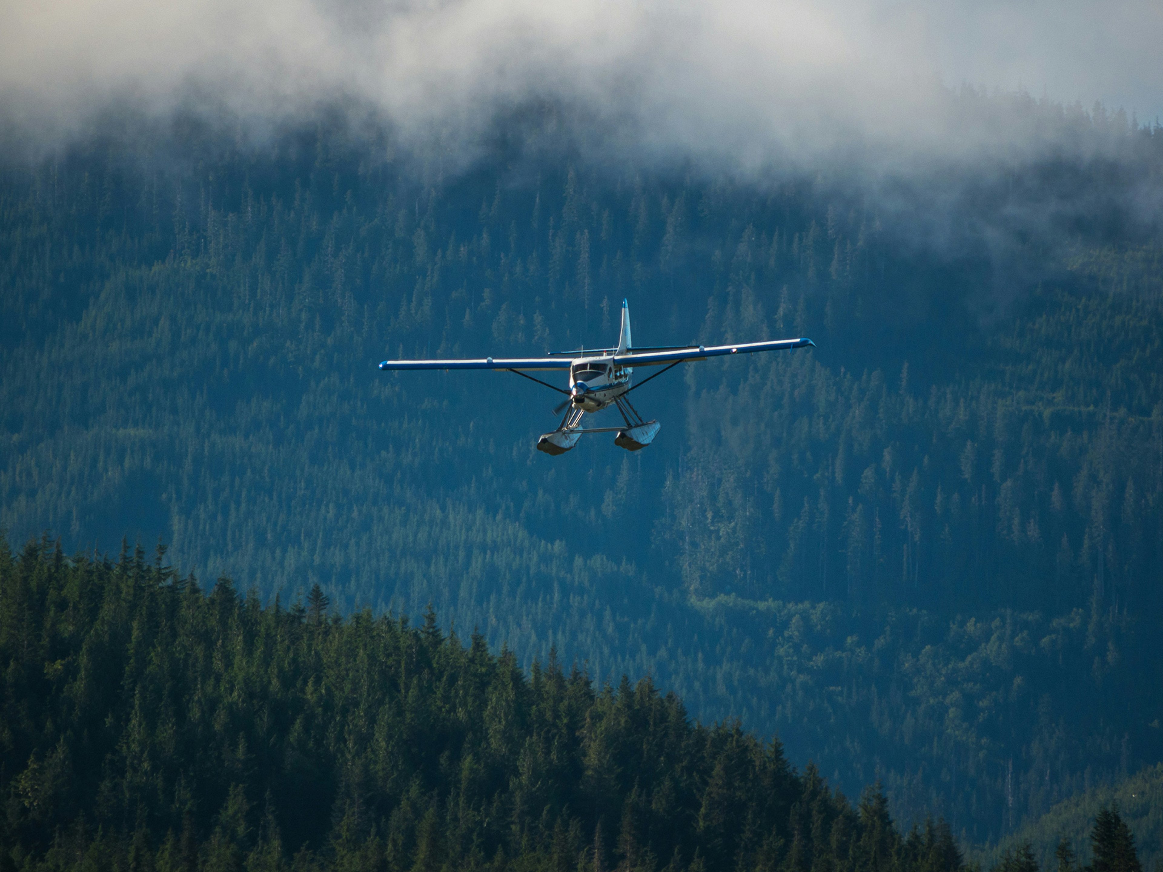 {generated} Un hydravion survolant des montagnes boisées embrumées évoque l’esprit d’aventure de la collection Breitling Emergency.