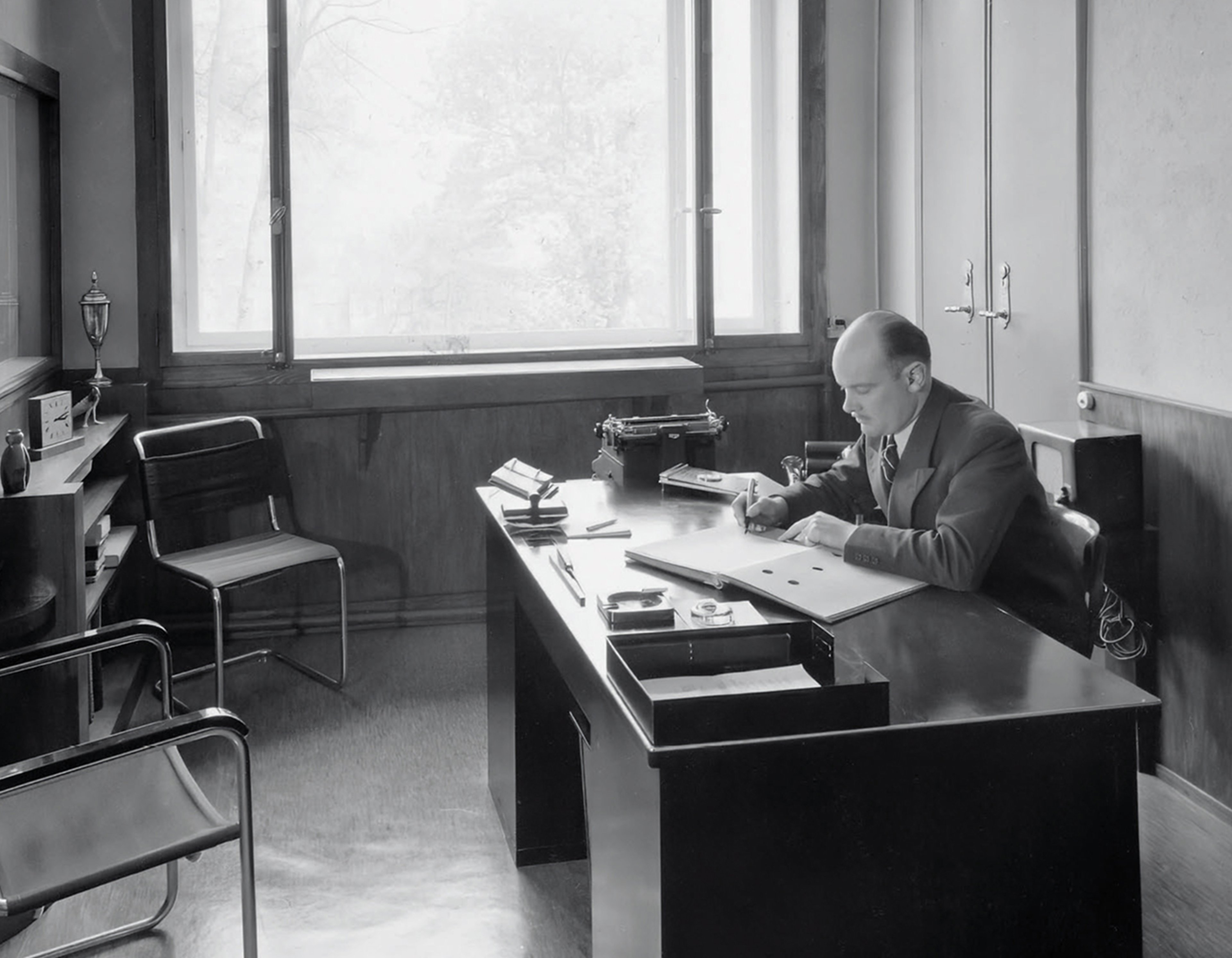 {generated} Historic office with a man writing at a tidy desk, reflecting Breitling Premier heritage in a refined, professional setting.