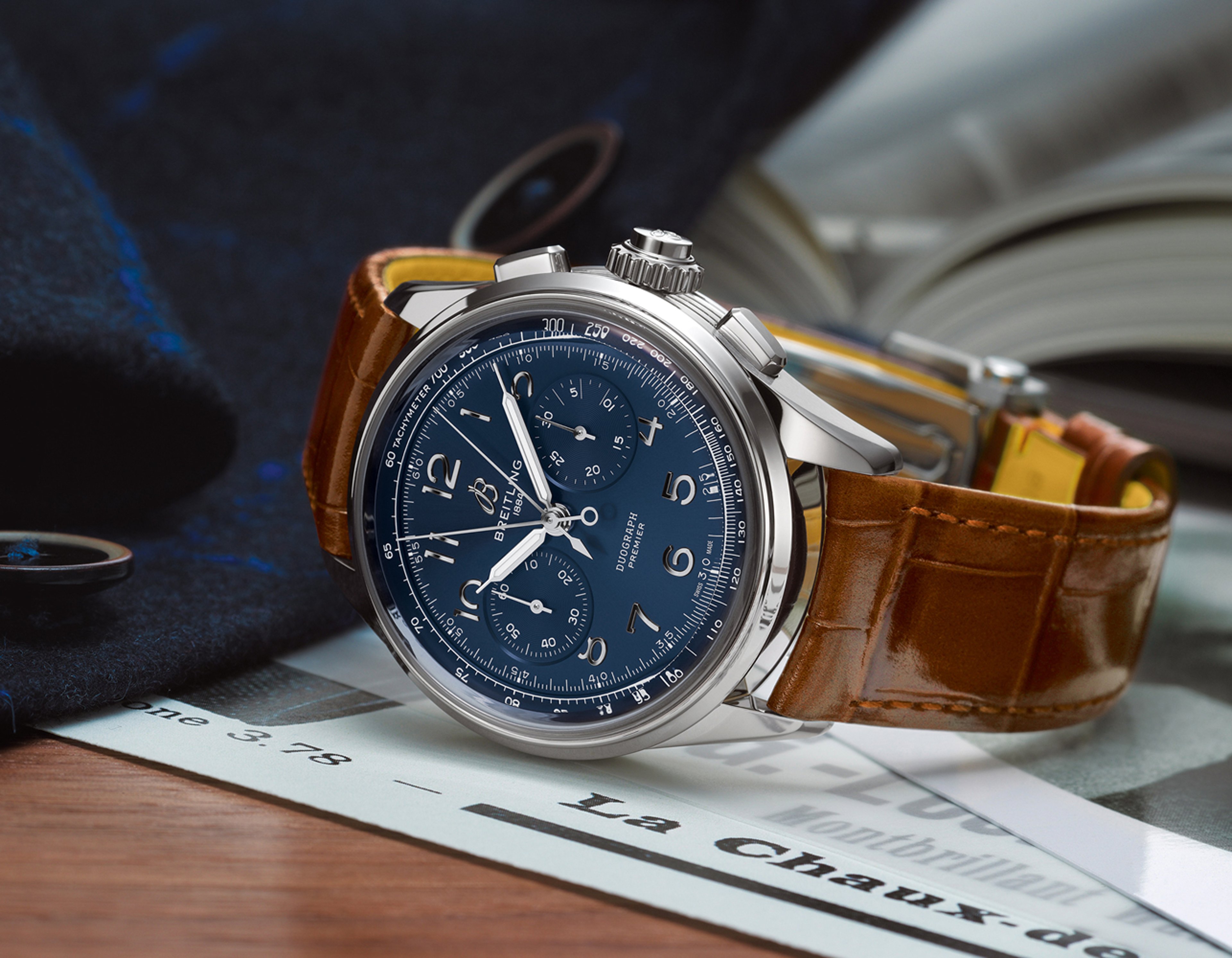 {generated} Breitling Premier watch with blue dial and brown leather strap rests on a desk beside papers and an open book
