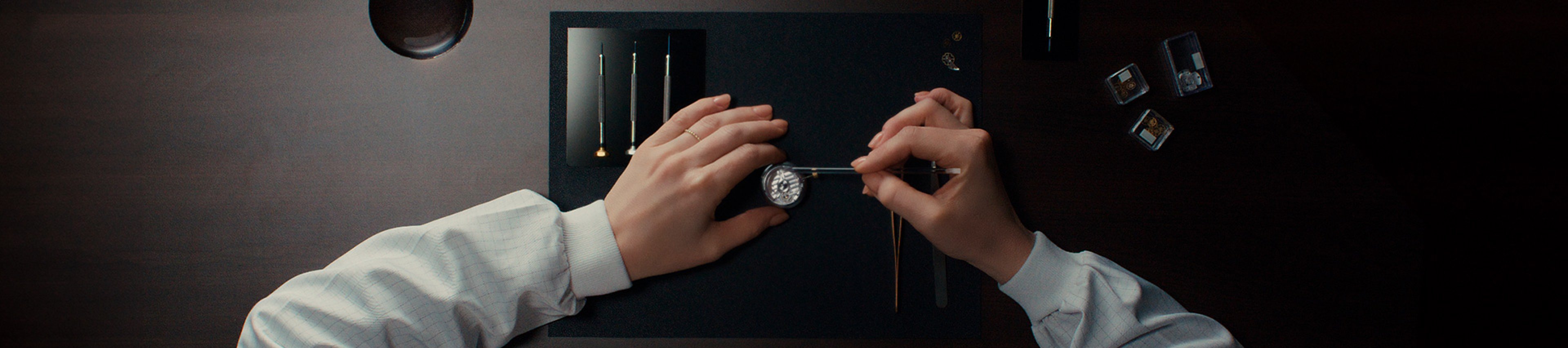 {generated} Watchmaker delicately services a Breitling movement on a dark workspace with precision tools arranged for meticulous care