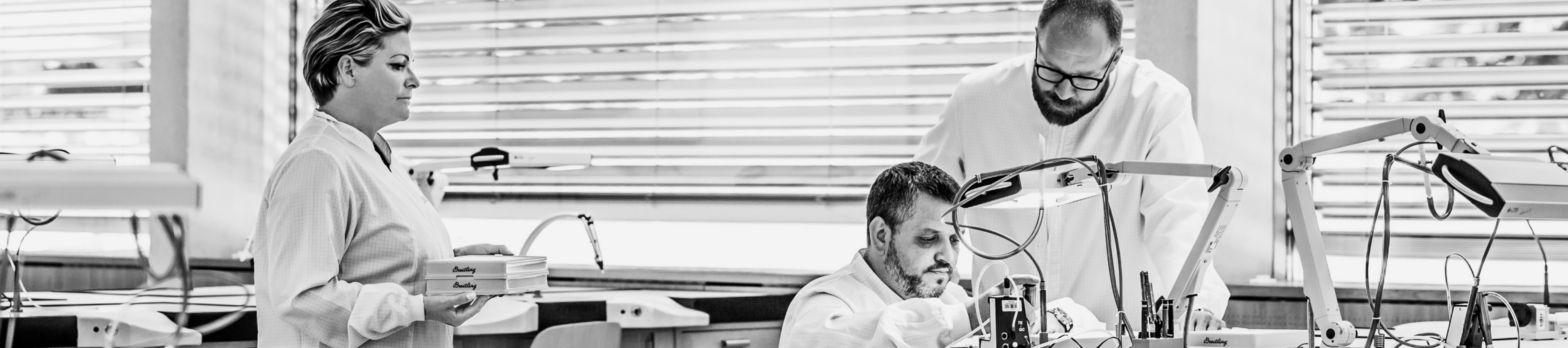 {generated} Watchmakers in a Breitling workshop collaborate at precision benches as trays are delivered, highlighting service expertise