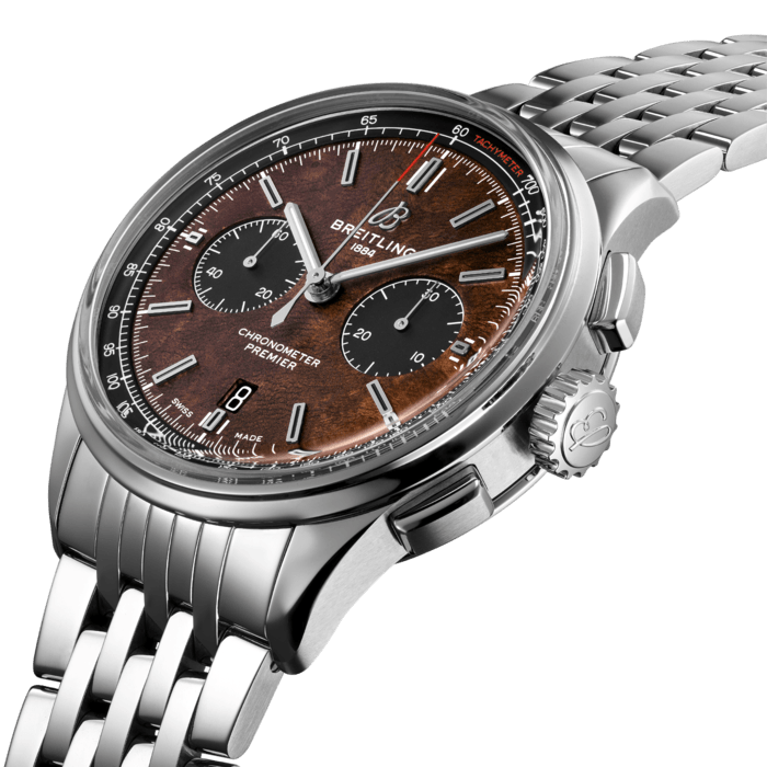 The Bentley Centenary Limited Edition in stainless-steel is presented on a stainless-steel bracelet. It is also available with a brown quilted calfskin strap. The watch has the unique brown burl elm dial, which is inspired by the wooden dashboard of the legendary 1929 “Blower” Bentley, the nickname given to the 4 ½ Litre Supercharged race cars driven by Sir Tim Birkin and the legendary Bentley Boys in the 1920s. The dial features contrasting black subdials and a white tachymeter scale on a black inner bezel around the dial, with a red tachymeter inscription. On the left side of the 42 mm steel case is a plate with an engraved “Bentley” inscription, which also owes its inspiration to the dashboard of the historic 1929 “Blower” Bentley. Inside the steel case is the Breitling Manufacture Caliber 01, a mechanical movement that has proven since years its performance and reliability.The movement is visible through a unique transparent caseback featuring a Bentley logo. The caseback is engraved with “1 OF 1000”.
