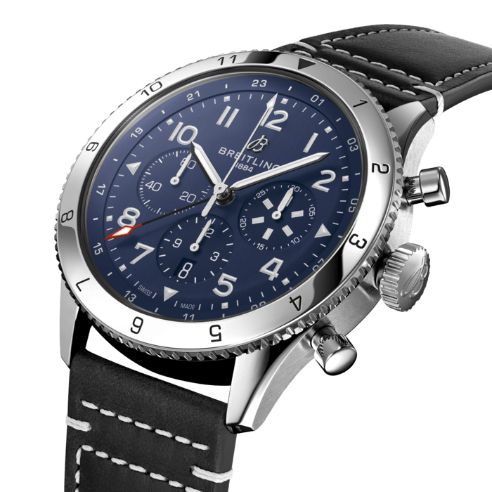 From brave first takeoffs to the birth of commercial air travel, Breitling’s history is inseparable from that of flight. In the 1930s, Breitling’s Huit Aviation department made its name inventing precision cockpit clocks. Two decades later, it introduced yet another novel flight instrument, this time in wearable form: the Ref. 765 AVI. That pioneering pilot’s watch provided the technical backdrop for today’s Super AVI, a collection inspired by the rugged spirit of famed early aircraft.
The Super AVI Tribute to Vought F4U Corsair honors one of those legends. As a WWII naval aircraft, the Corsair had to make tricky takeoffs and landings from carriers and remote landing strips. Speed and lift were of the essence, and the plane came through with flying colors, becoming the first single-engine fighter to crack the 400 mph (640 km/h) mark, while also providing an exceptional rate of climb. Its “bent-wing” design, oversized propeller and signature blue livery make it an emblem of aviation history.
As a true pilot’s watch designed to withstand the rigors of a vintage cockpit, the Super AVI Tribute to Vought F4U Corsair features large, highly legible Arabic numerals on the dial and bezel.
The oversized crown and knurled bezel on its sturdy 46mm case provide optimal grip, even in a pilot’s gloved hands. Top-stitched calfskin straps give a nod to the seams found on classic flight gear, while the optional stainless-steel bracelet provides an elegant alternative. Pilots and other travelers will appreciate the ability to track a second time zone using the 24-hour marking on the inner bezel and the red-tipped GMT hand. The engine of the Super AVI is the COSC-certified Breitling Manufacture Caliber B04 movement, which provides approximately 70-hours of power reserve.